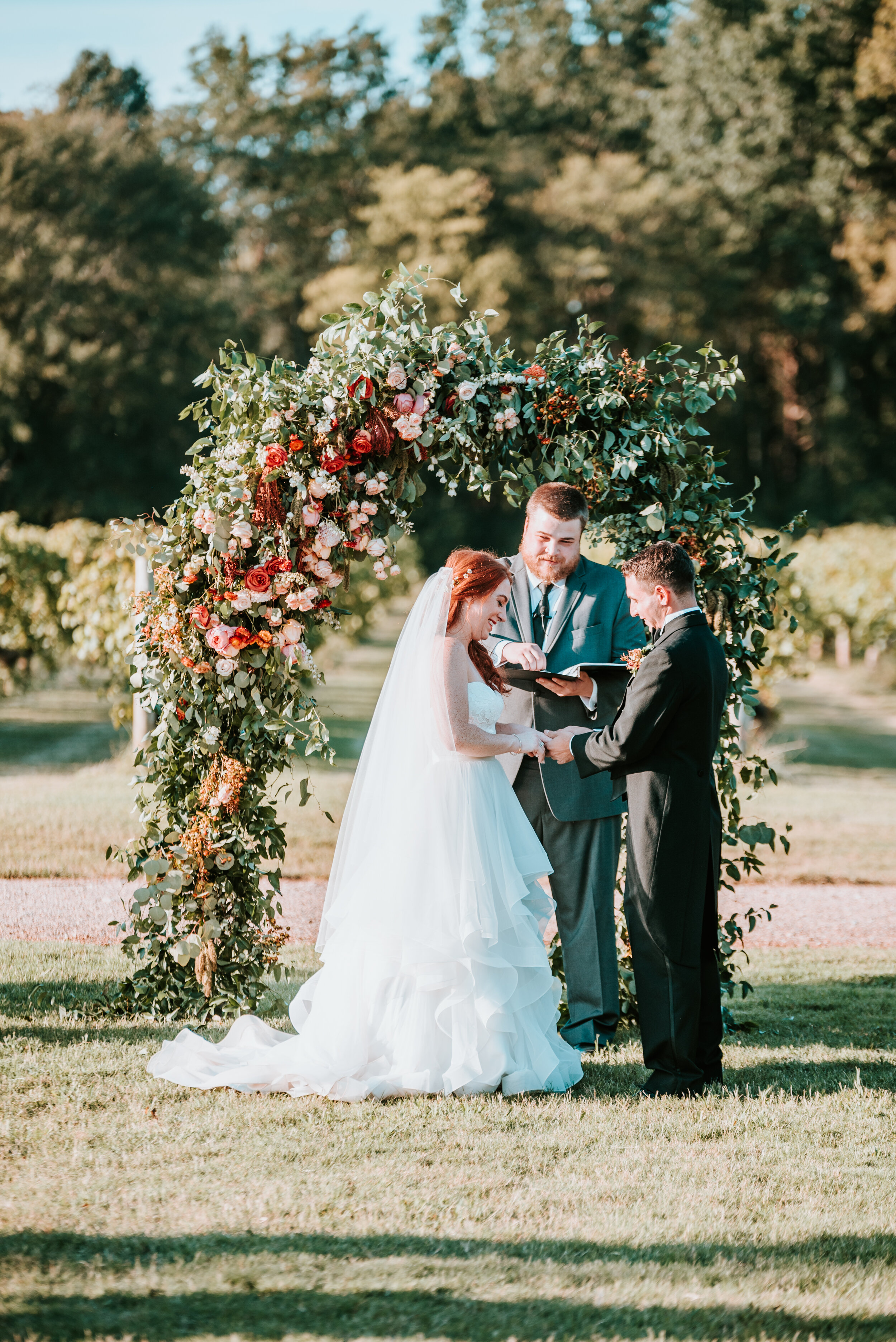 Lush floral arch for a fall wedding at Long Hollow Gardens with untamed greenery, berries, and rust orange garden roses.