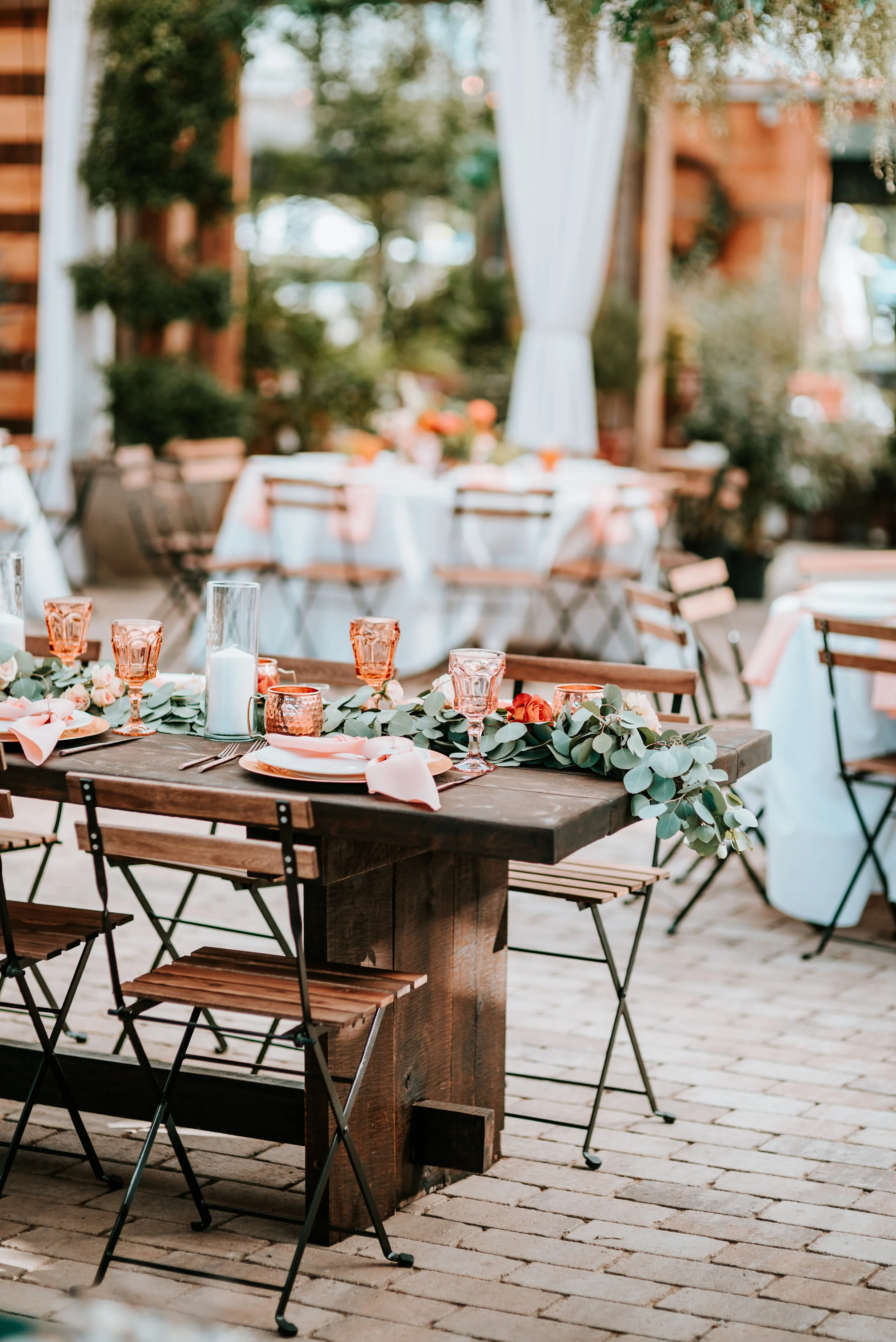 Eucalyptus table runner with floral accents of burnt orange and peach roses and ranunculus. Nashville wedding floral designer.