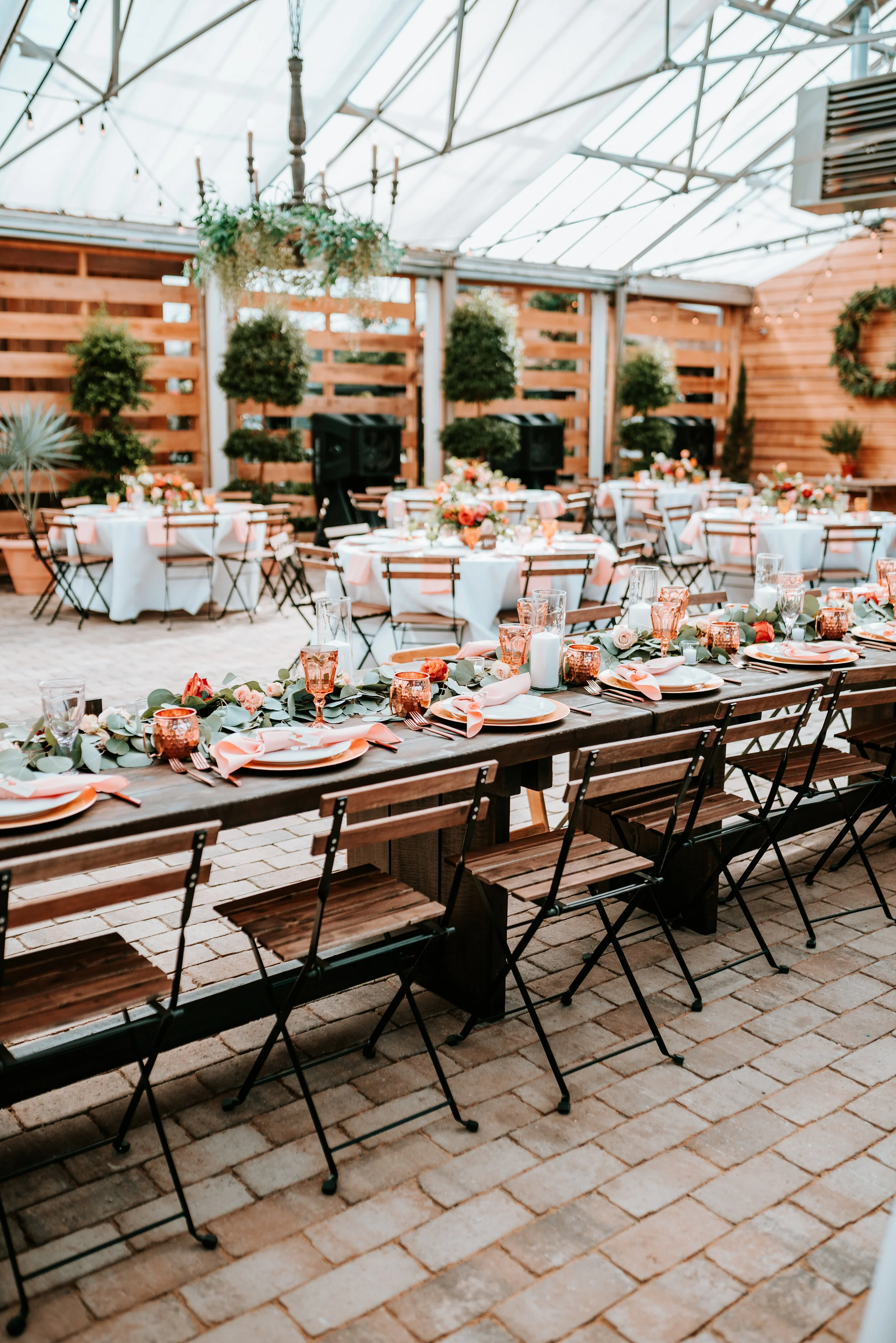 Eucalyptus table runner with floral accents of burnt orange and peach roses and ranunculus. Nashville wedding floral designer.
