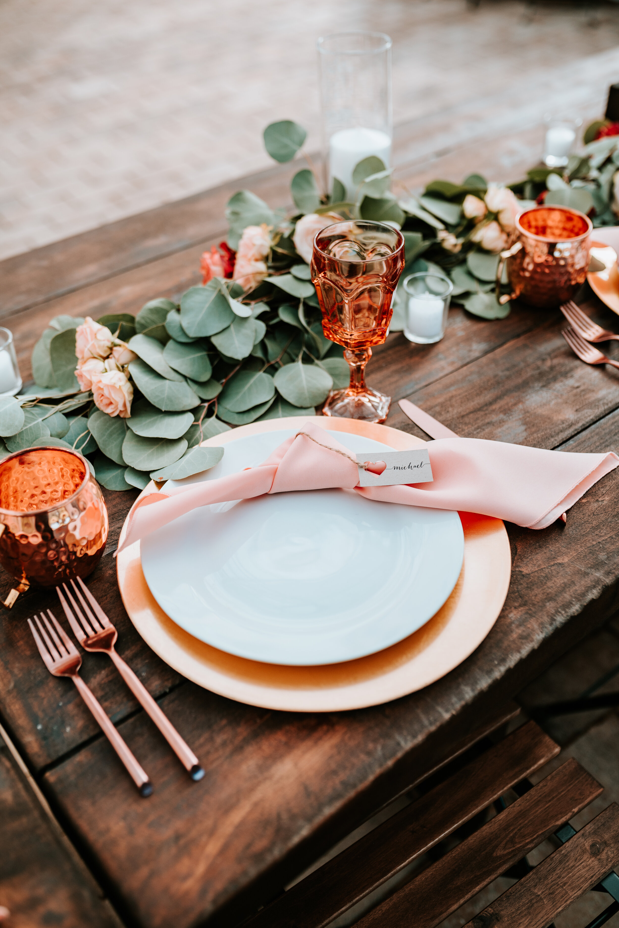 Eucalyptus table runner with floral accents of burnt orange and peach roses and ranunculus. Nashville wedding floral designer.
