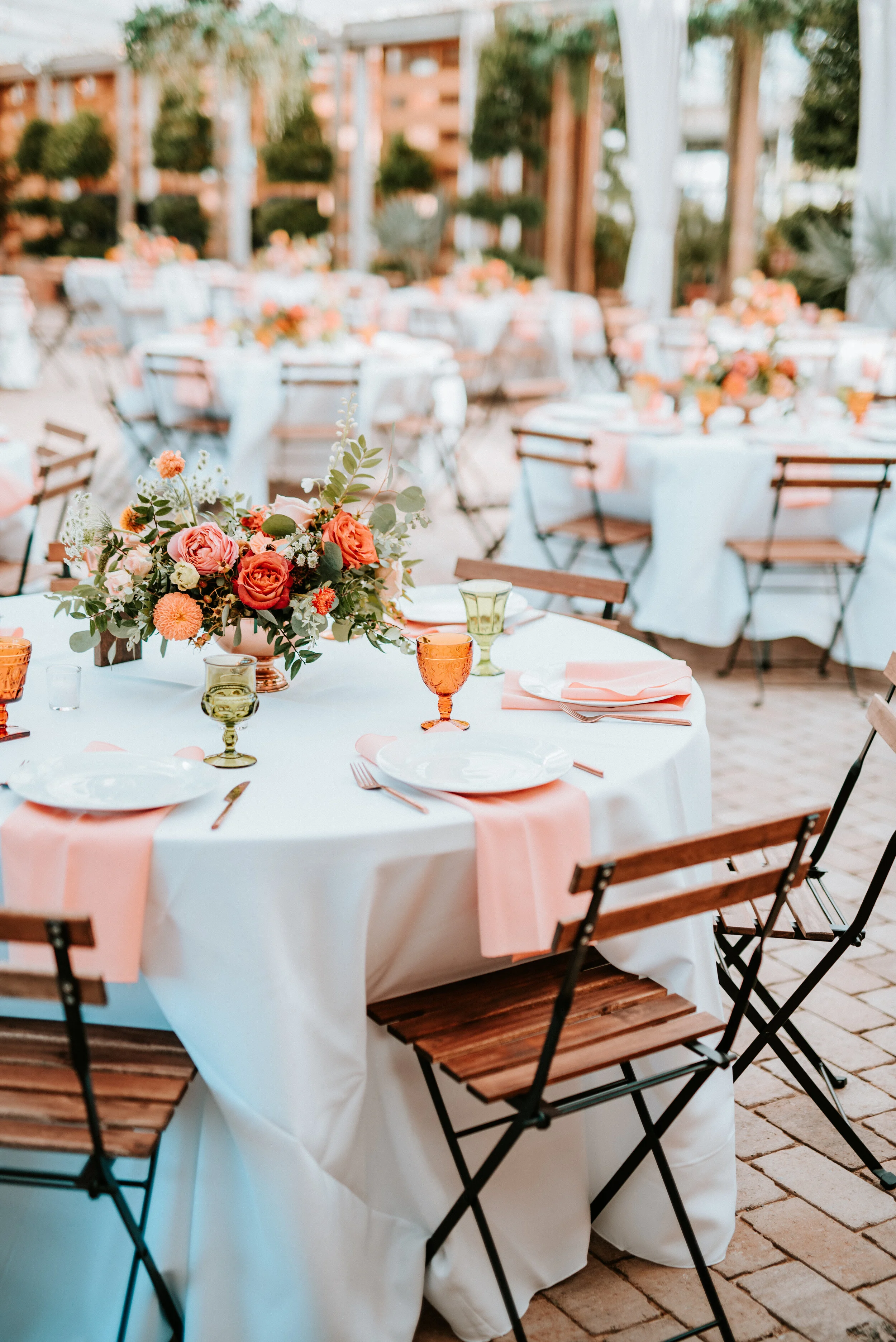 Greenhouse wedding reception with orange and peach flower arrangements of garden roses, ranunculus, berries, and wildflowers with asymmetrical, trailing greenery. Nashville wedding floral design.