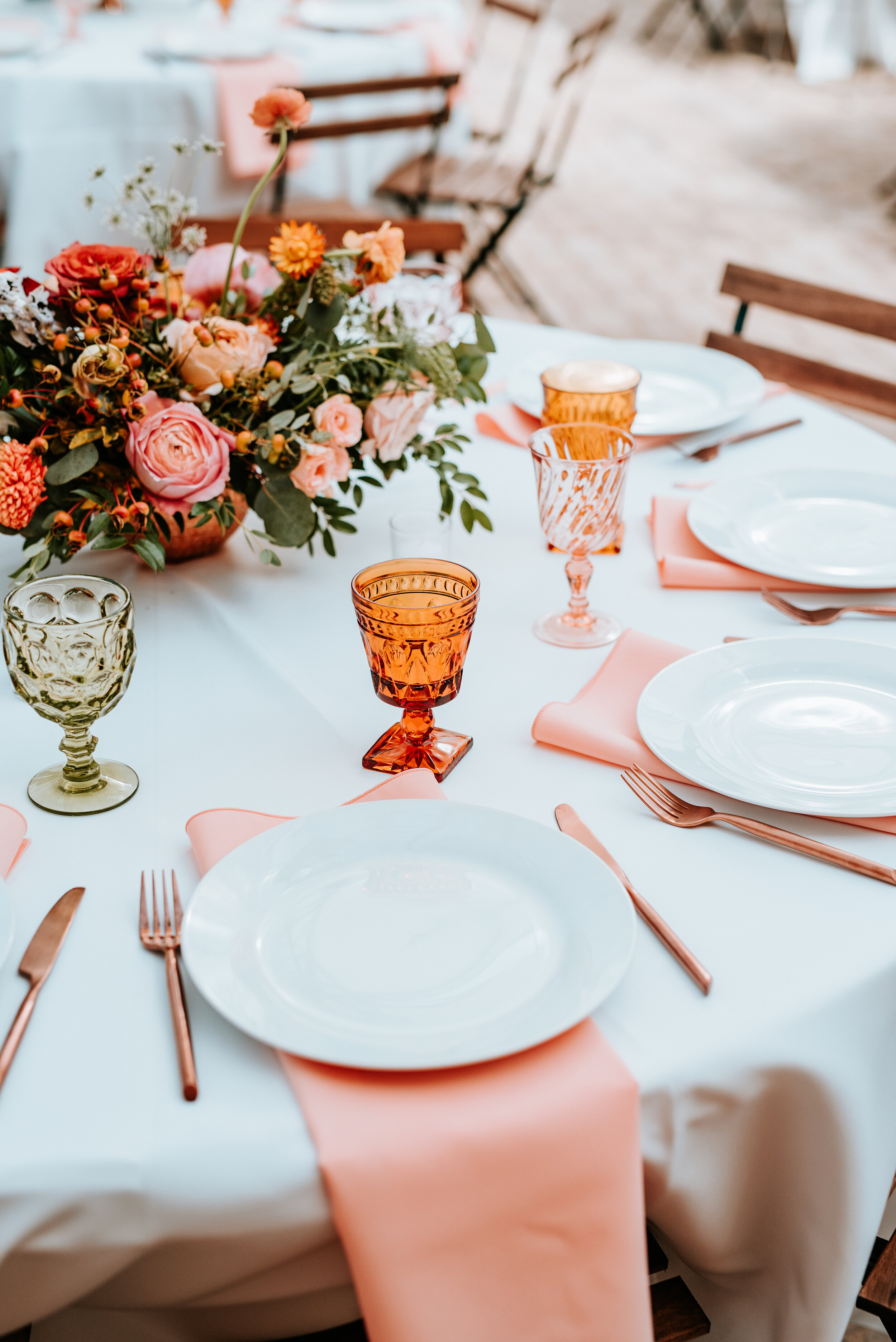Greenhouse wedding reception with orange and peach flower arrangements of garden roses, ranunculus, berries, and wildflowers with asymmetrical, trailing greenery. Nashville wedding floral design.