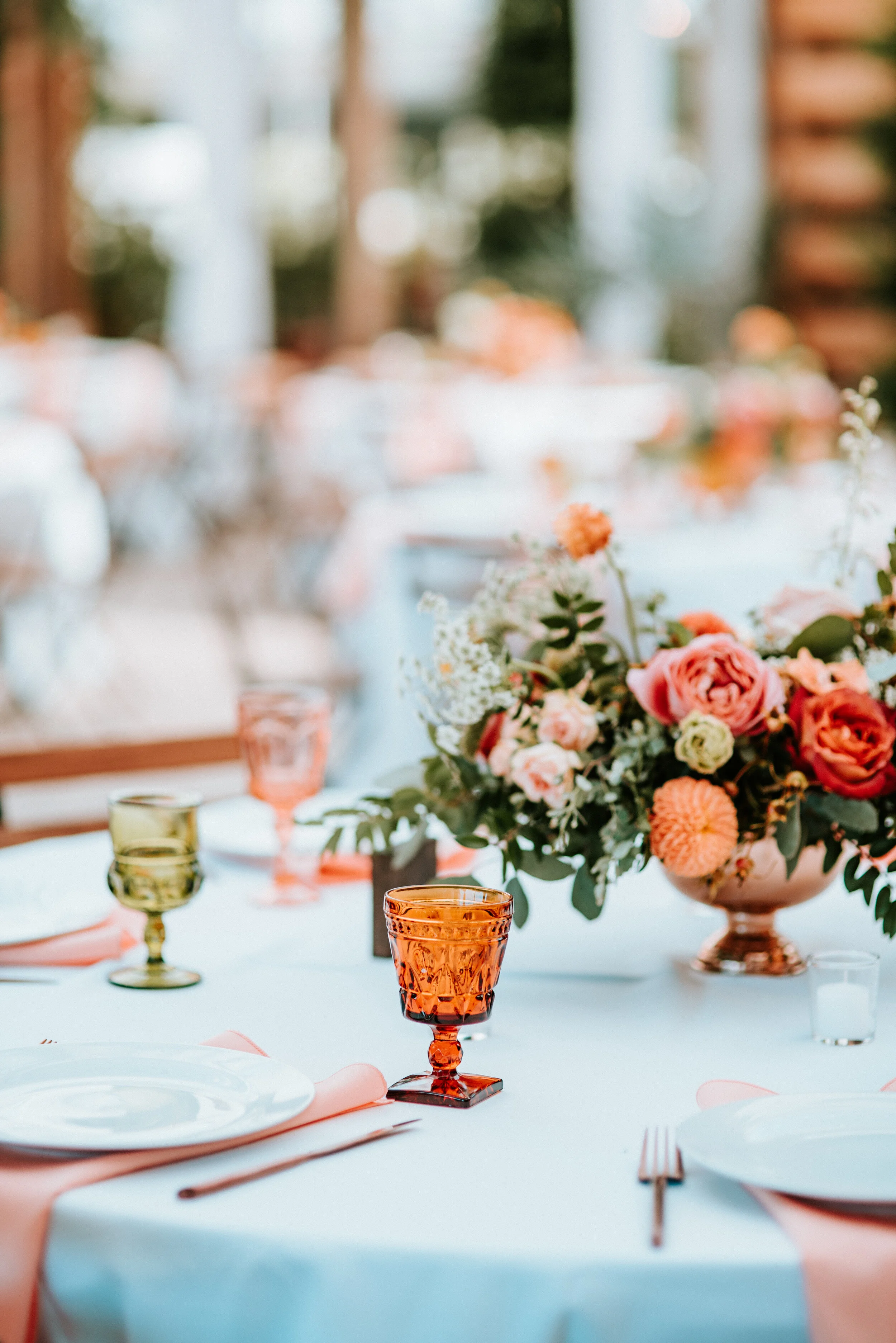 Greenhouse wedding reception with orange and peach flower arrangements of garden roses, ranunculus, berries, and wildflowers with asymmetrical, trailing greenery. Nashville wedding floral design.