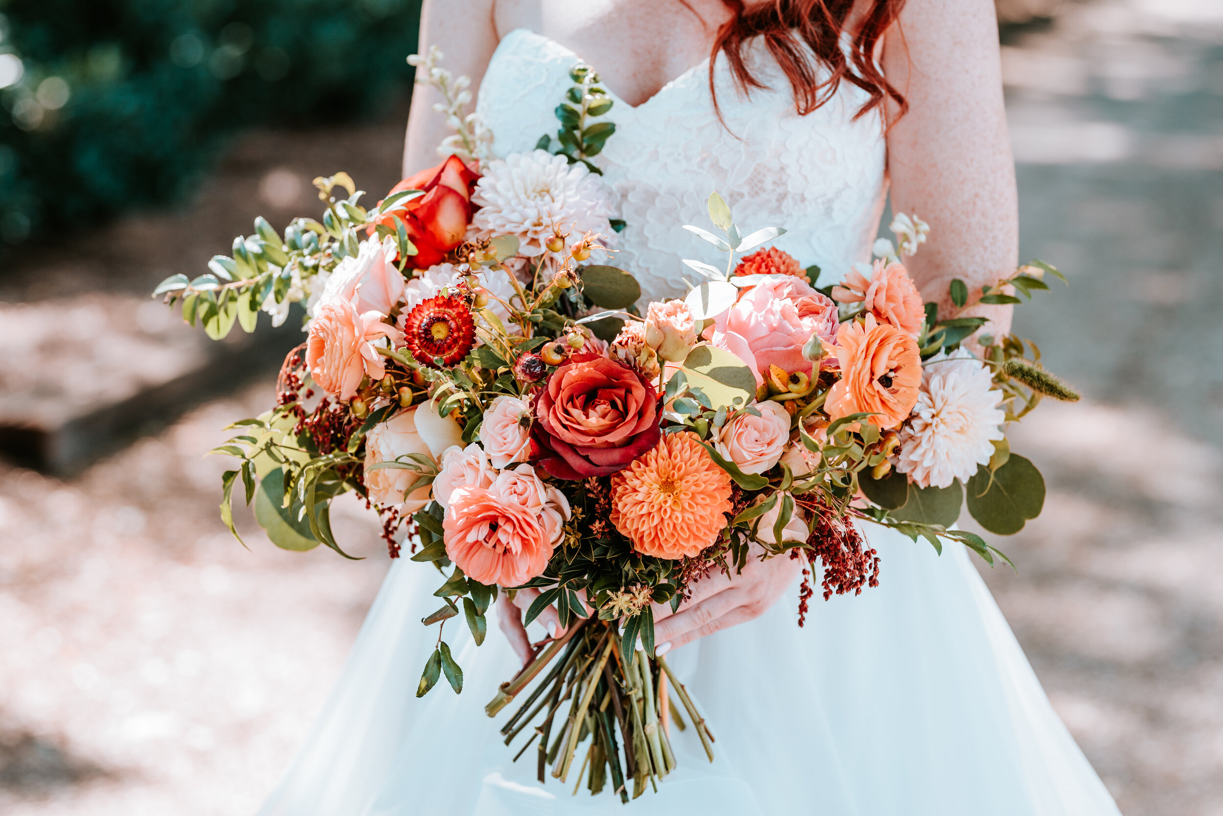 Fall bridal bouquet with garden roses, dahlias, and ranunculus in shades of burnt orange and peach, autumnal berries, and lush greenery. Nashville Wedding Floral Design.