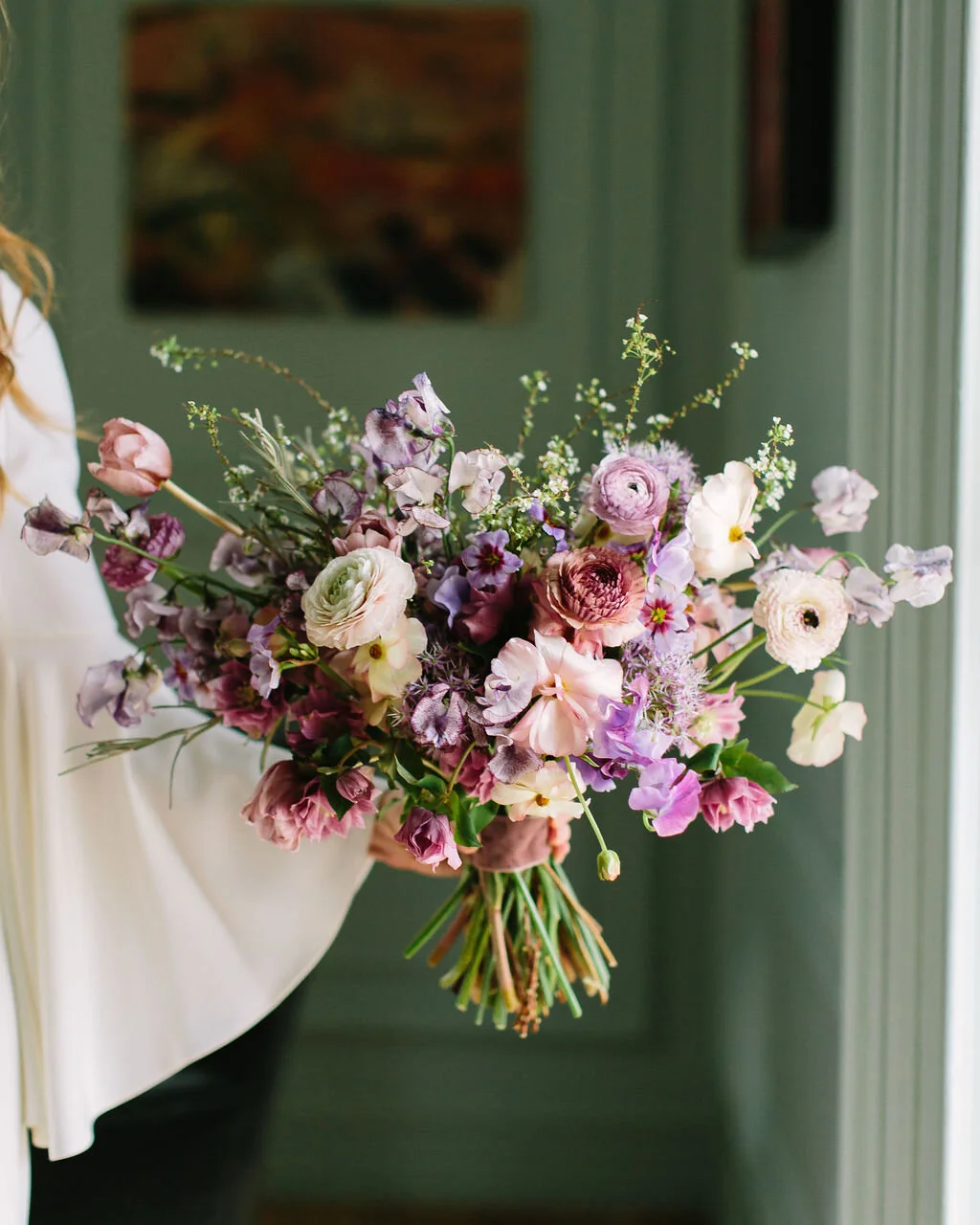 Whimsical and organic purple bridal bouquet with delicate spring flowers like spirea, ranunculus, sweet peas, and tulips. Nashville wedding florist.