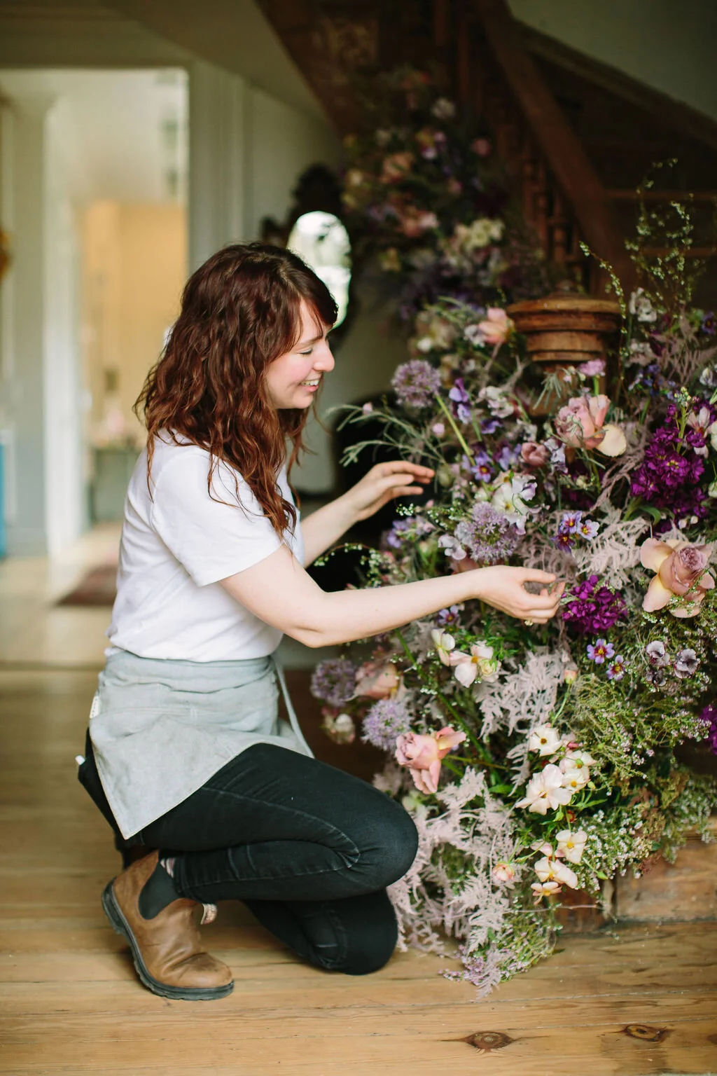 Spiral staircase with a lush, airy floral installation in a lavender and lilac color palette with spirea, painted plumosa ferns, heather, allium, ranunculus, and garden roses. Nashville Wedding Floral Design.