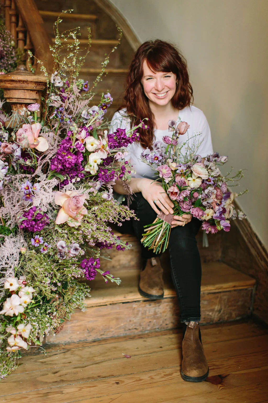 Spiral staircase with a lush, airy floral installation in a lavender and lilac color palette with spirea, painted plumosa ferns, heather, allium, ranunculus, and garden roses. Nashville Wedding Floral Design.