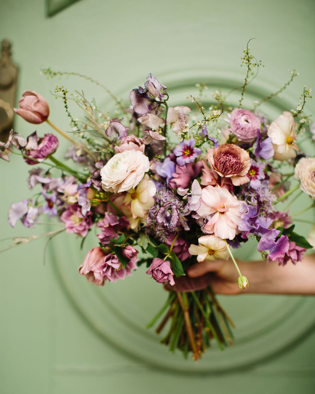 Whimsical and organic purple bridal bouquet with delicate spring flowers like spirea, ranunculus, sweet peas, and tulips. Nashville wedding florist.