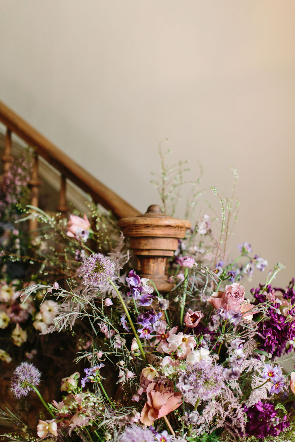 Spiral staircase with a lush, airy floral installation in a lavender and lilac color palette with spirea, painted plumosa ferns, heather, allium, ranunculus, and garden roses. Nashville Wedding Floral Design.