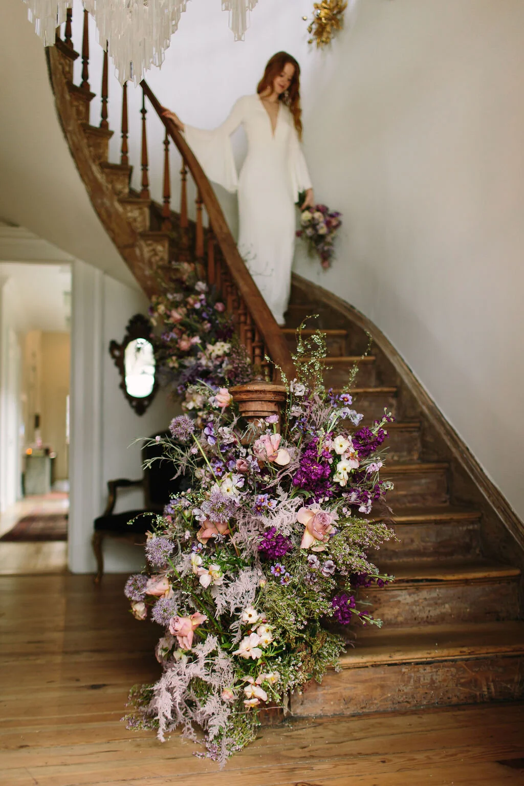 Spiral staircase with a lush, airy floral installation in a lavender and lilac color palette with spirea, painted plumosa ferns, heather, allium, ranunculus, and garden roses. Nashville Wedding Floral Design.