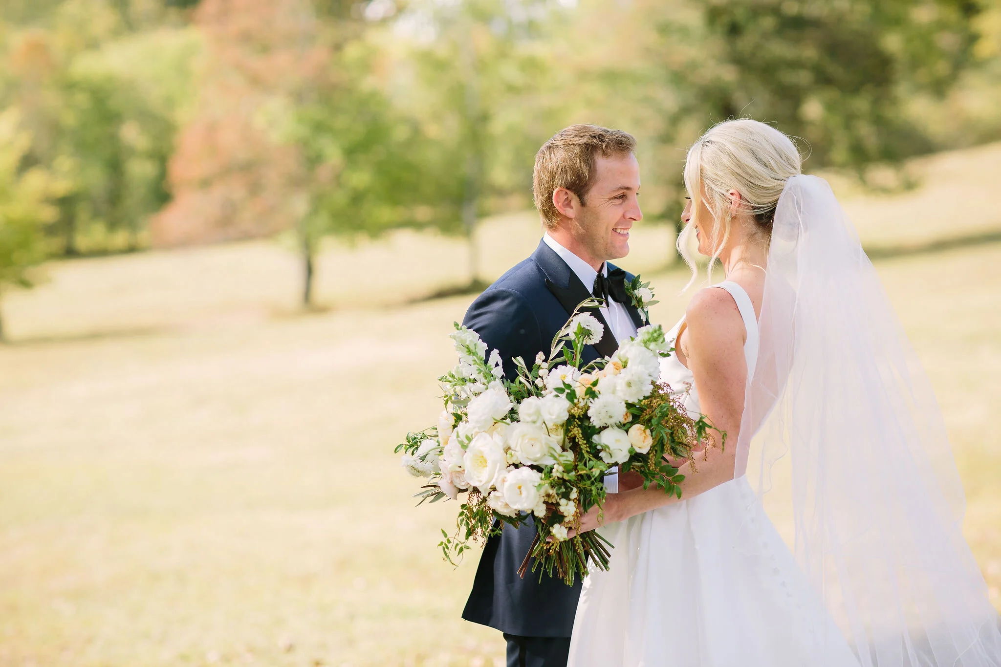 All white bridal bouquet with garden roses, ranunculus, snapdragons, scabiosa, and trailing greenery. Organic wedding floral design in Nashville, TN.