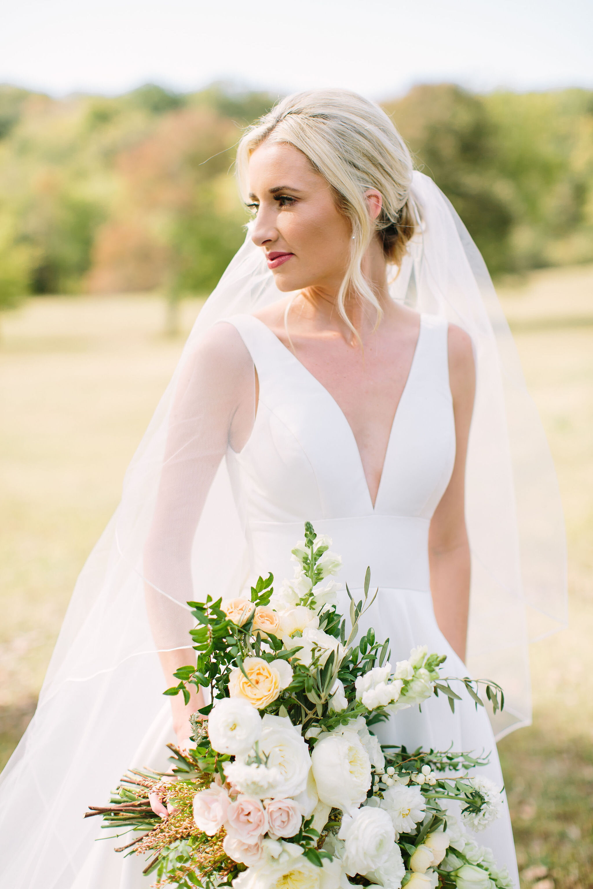 All white bridal bouquet with garden roses, ranunculus, snapdragons, scabiosa, and trailing greenery. Organic wedding floral design in Nashville, TN.