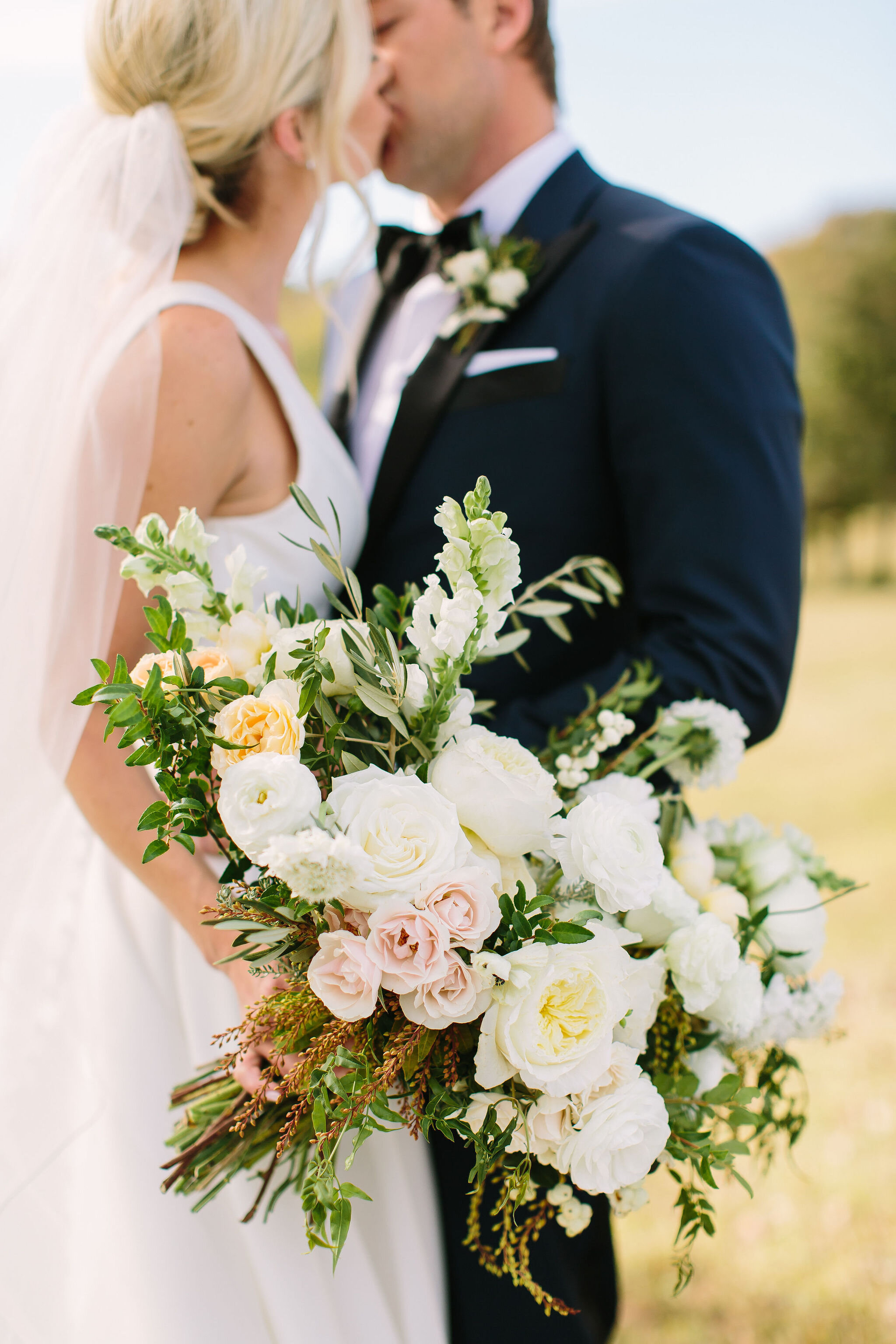 All white bridal bouquet with garden roses, ranunculus, snapdragons, scabiosa, and trailing greenery. Organic wedding floral design in Nashville, TN.