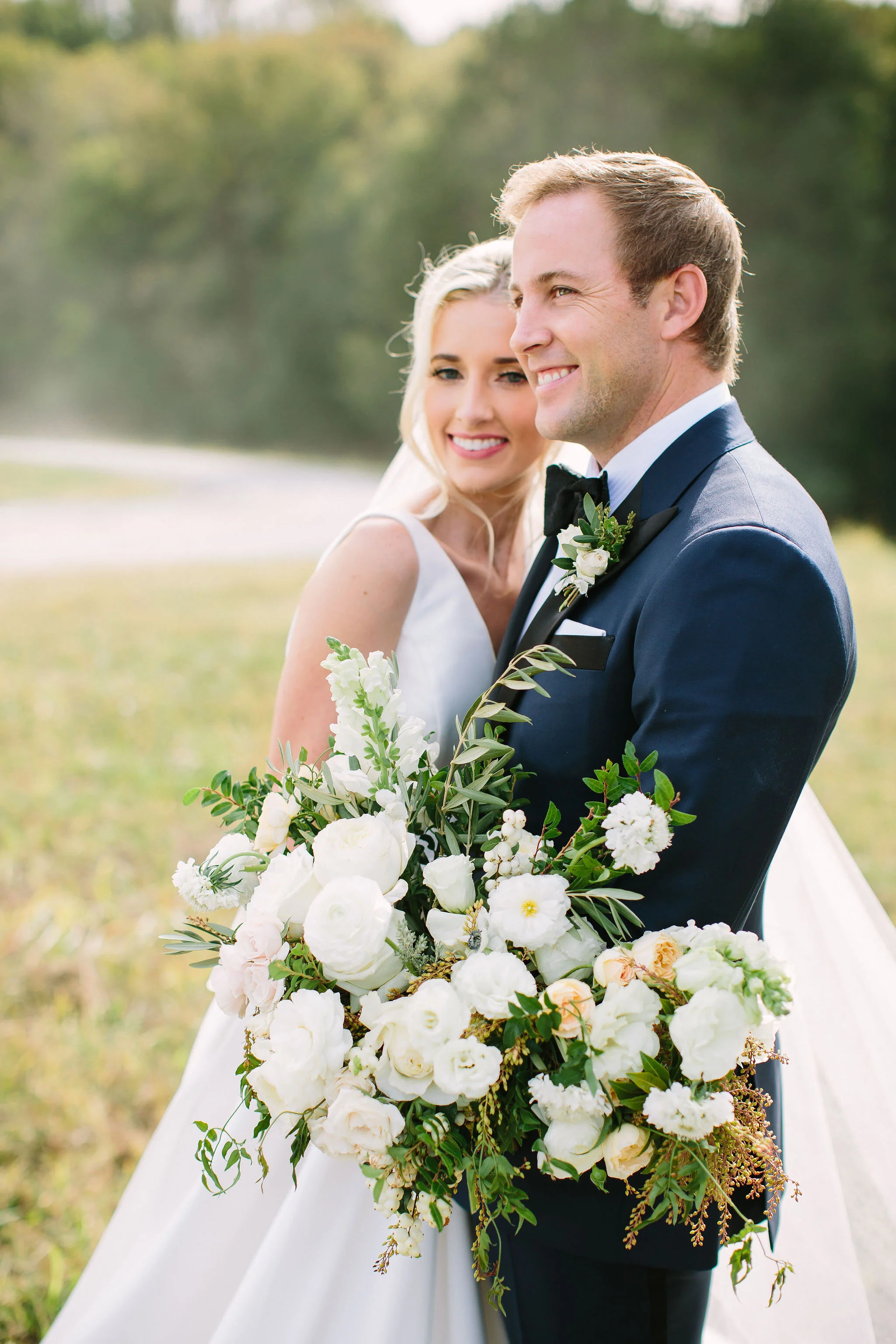 All white bridal bouquet with garden roses, ranunculus, snapdragons, scabiosa, and trailing greenery. Organic wedding floral design in Nashville, TN.