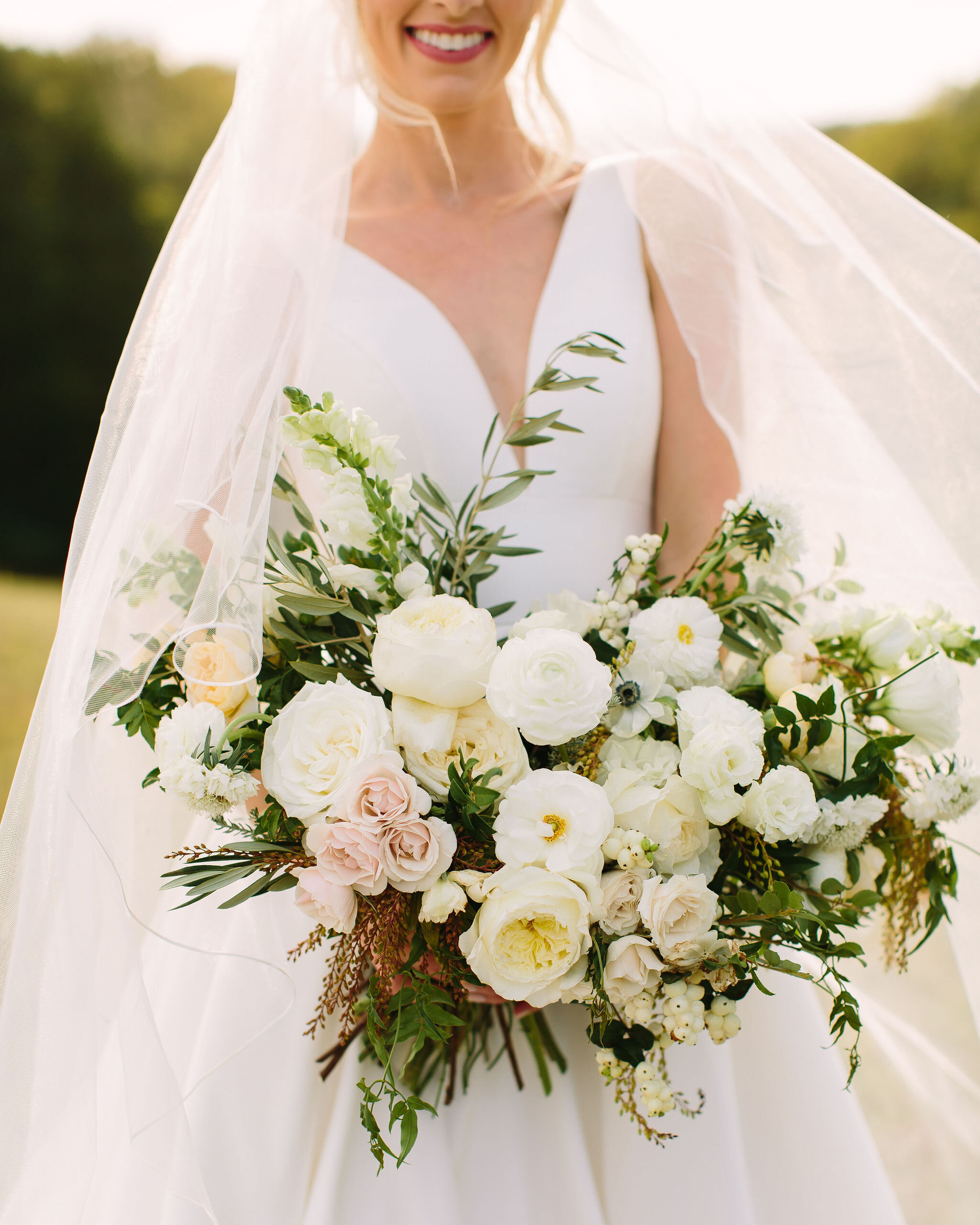 All white bridal bouquet with garden roses, ranunculus, snapdragons, scabiosa, and trailing greenery. Organic wedding floral design in Nashville, TN.