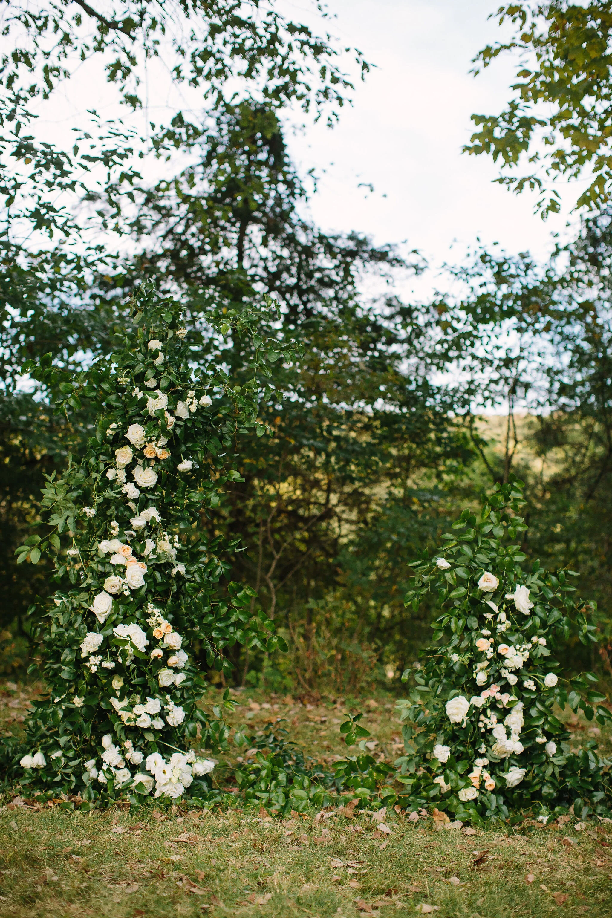 Growing, asymmetrical floral installation for the wedding ceremony backdrop. All white flowers and natural greenery. Nashville wedding florist.