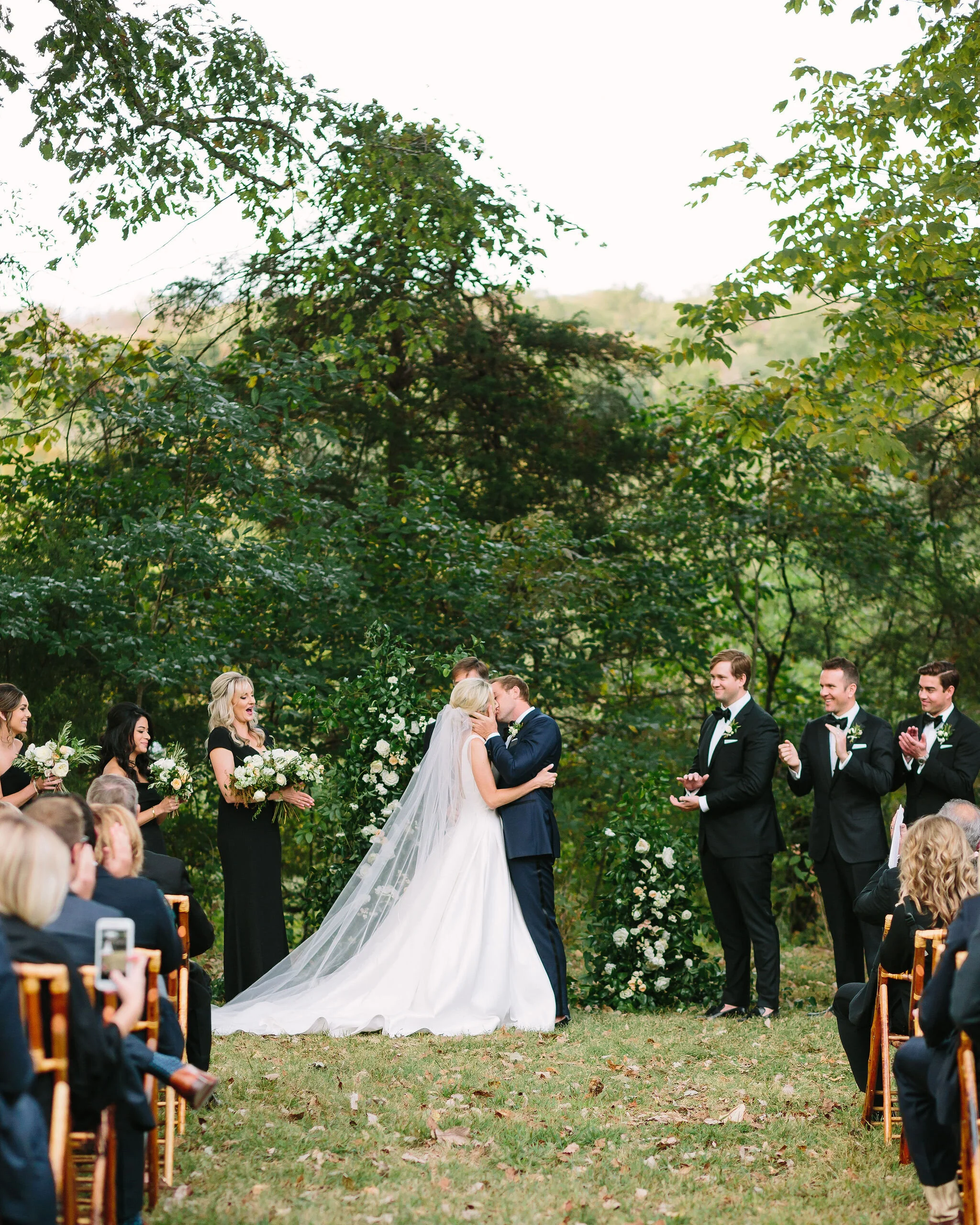 Growing, asymmetrical floral installation for the wedding ceremony backdrop. All white flowers and natural greenery. Nashville wedding florist.