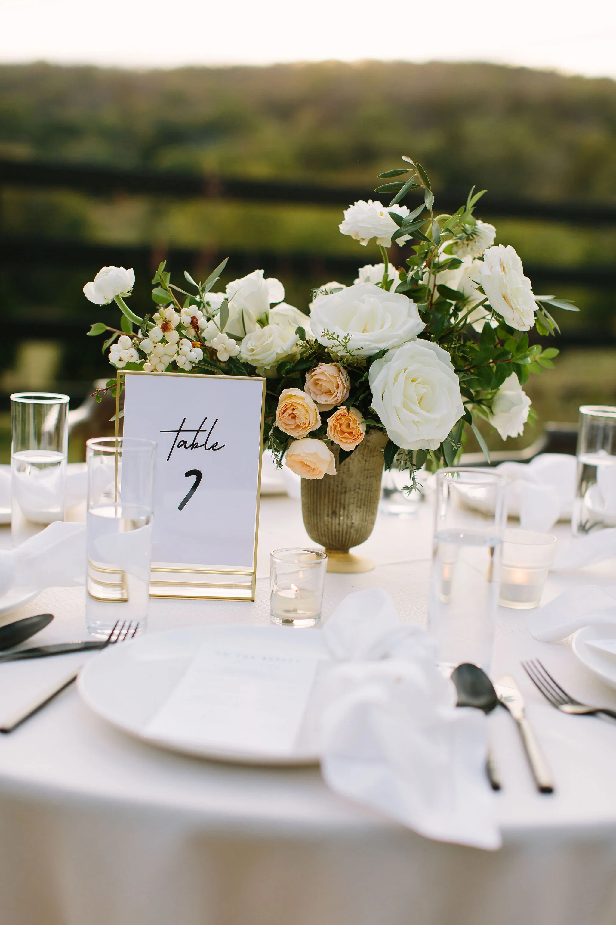 Whimsical floral centerpiece in a gold compote vase with white ranunculus, garden roses, and greenery. Nashville wedding florist at Bloomsbury Farm.