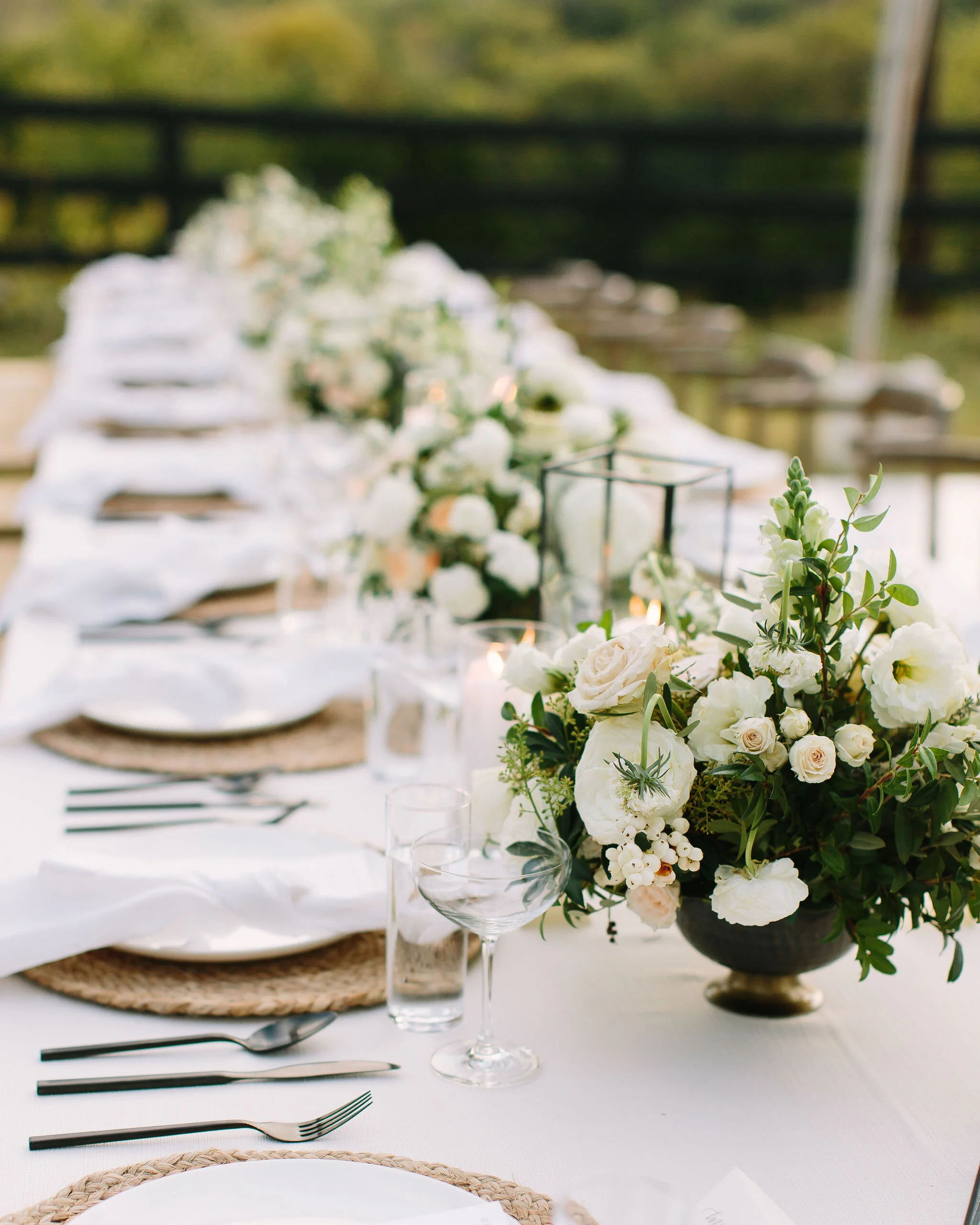 Whimsical floral centerpiece in a gold compote vase with white ranunculus, garden roses, and greenery. Nashville wedding florist at Bloomsbury Farm.