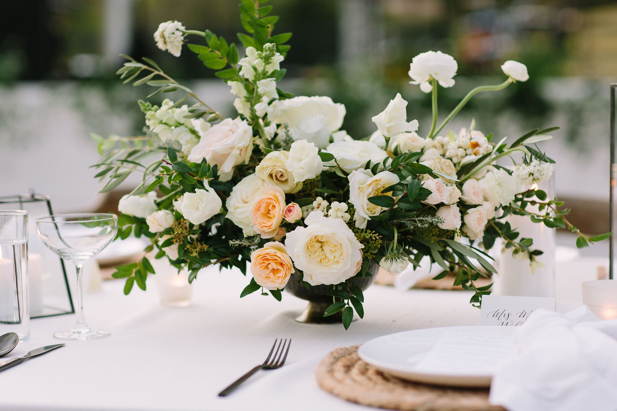 Whimsical floral centerpiece in a gold compote vase with white ranunculus, garden roses, and greenery. Nashville wedding florist at Bloomsbury Farm.