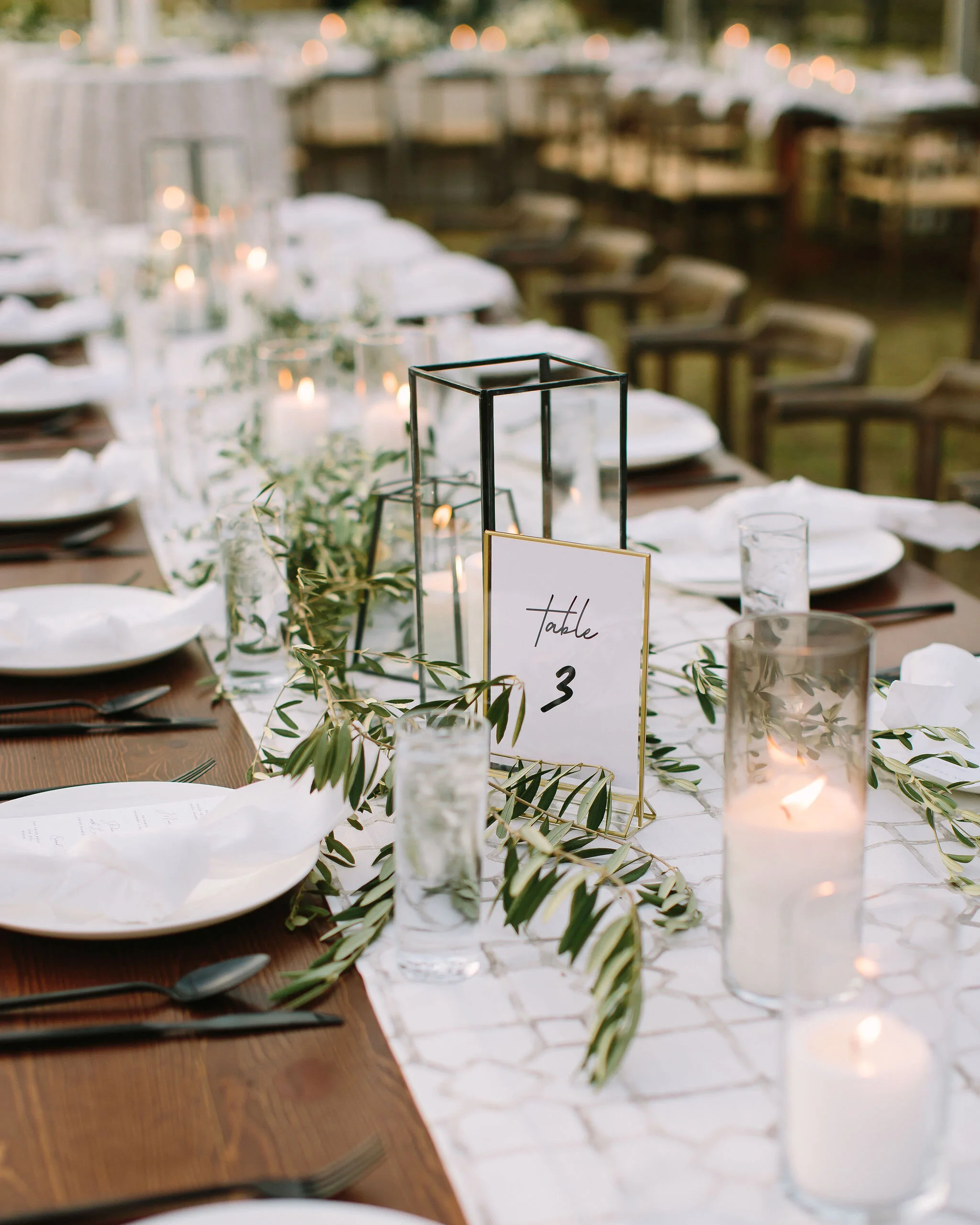Olive branches styled around minimal black lanterns. Nashville wedding floral design.