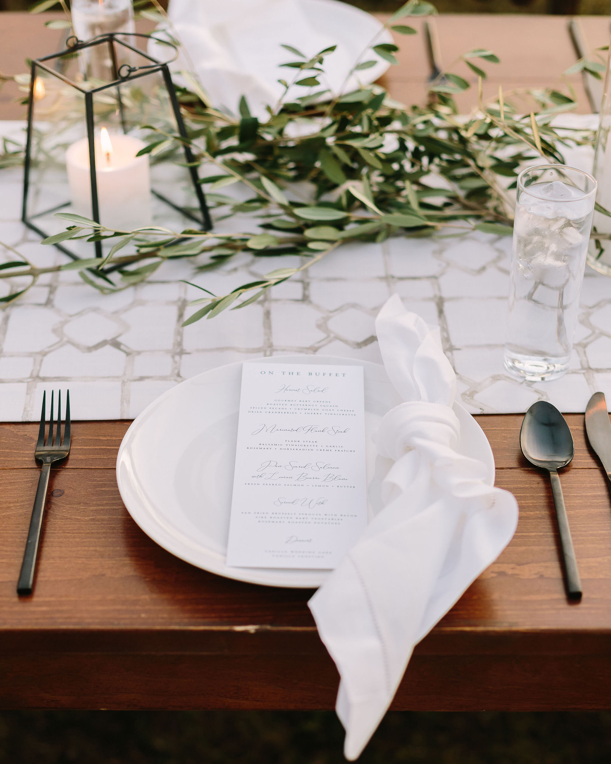 Olive branches styled around minimal black lanterns. Nashville wedding floral design.