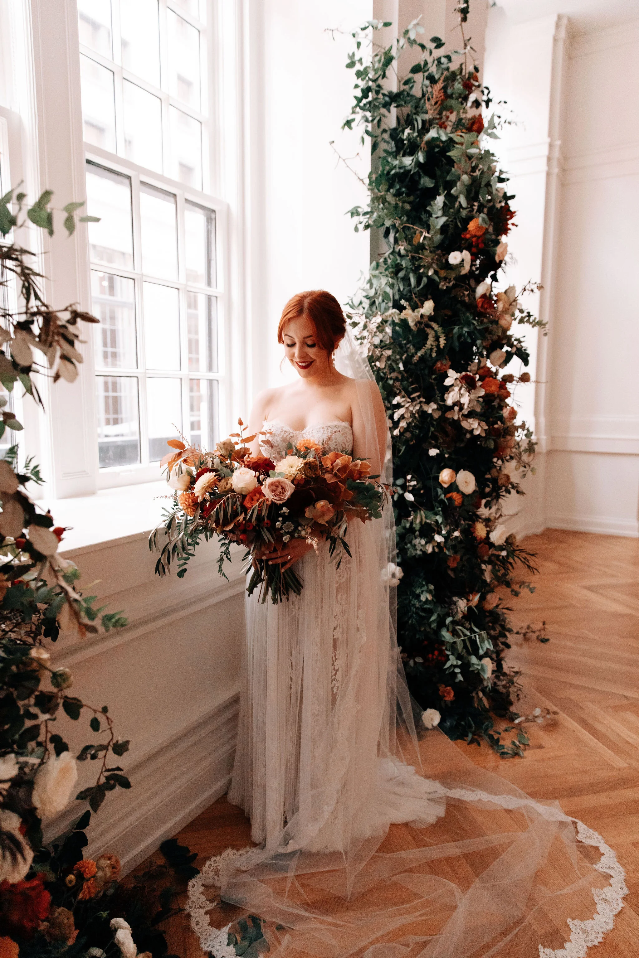 Bridal bouquet in shades of burnt orange, rust, burgundy, copper, and greenery, with dahlias, ranunculus, rosehips, and olive branches. Nashville wedding floral designer.