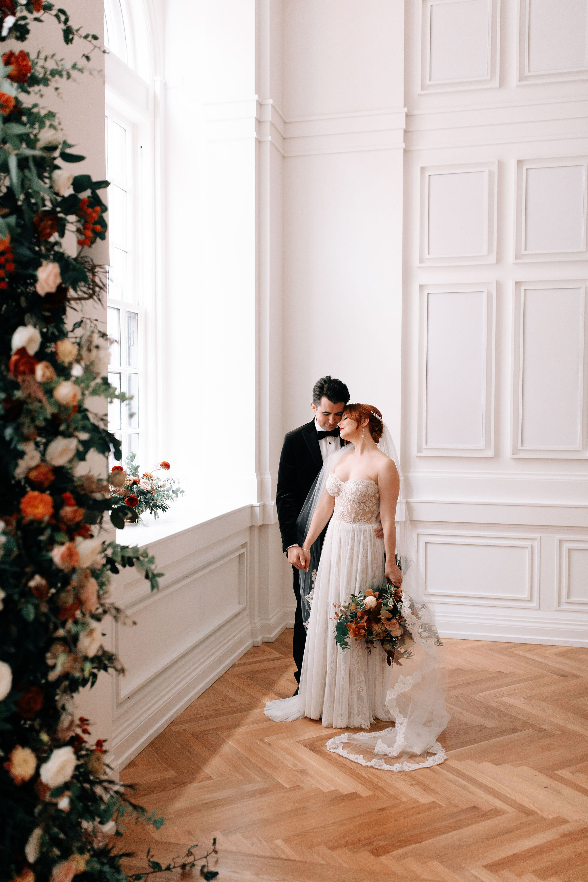 Growing floral installation on either side of the window for the wedding ceremony backdrop, with untamed greenery, rusty orange and burnt sienna garden roses, and lots of texture. Nashville wedding florist at the Noelle hotel.