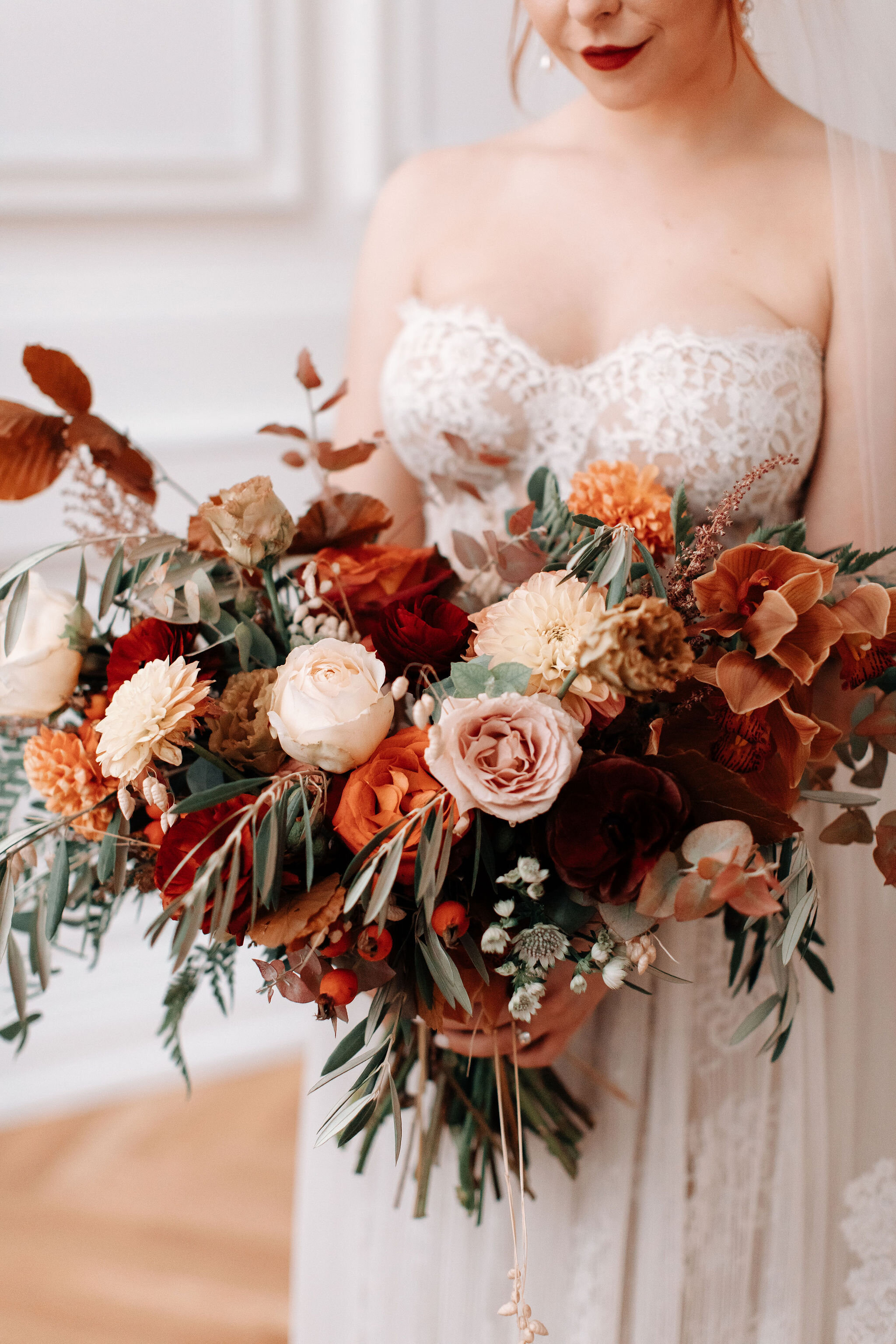 Bridal bouquet in shades of burnt orange, rust, burgundy, copper, and greenery, with dahlias, ranunculus, rosehips, and olive branches. Nashville wedding floral designer.