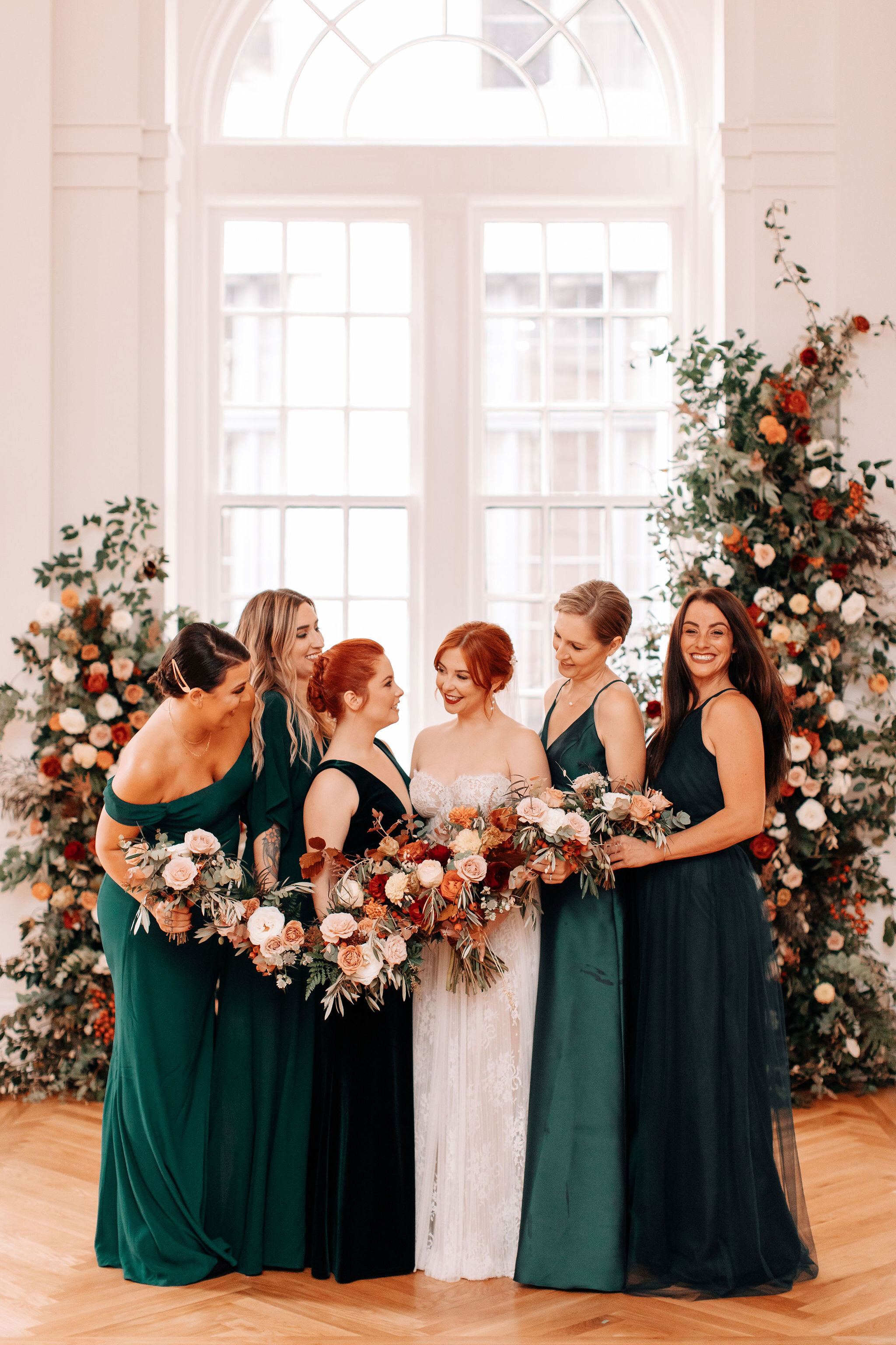 Emerald green bridesmaid dresses, black tuxes, redhead bride, and rusty red and burnt orange florals with natural greenery. Nashville wedding florist at the Noelle.