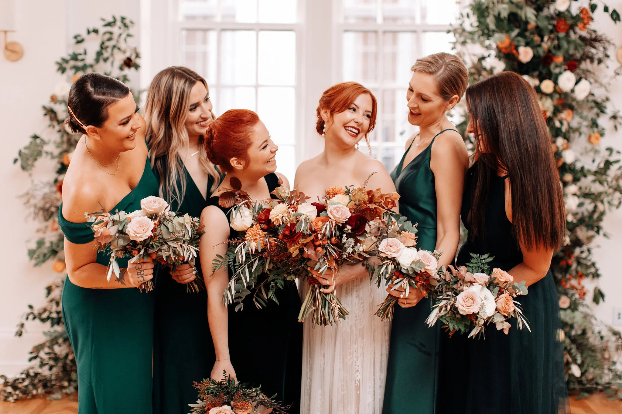 Emerald green bridesmaid dresses, black tuxes, redhead bride, and rusty red and burnt orange florals with natural greenery. Nashville wedding florist at the Noelle.