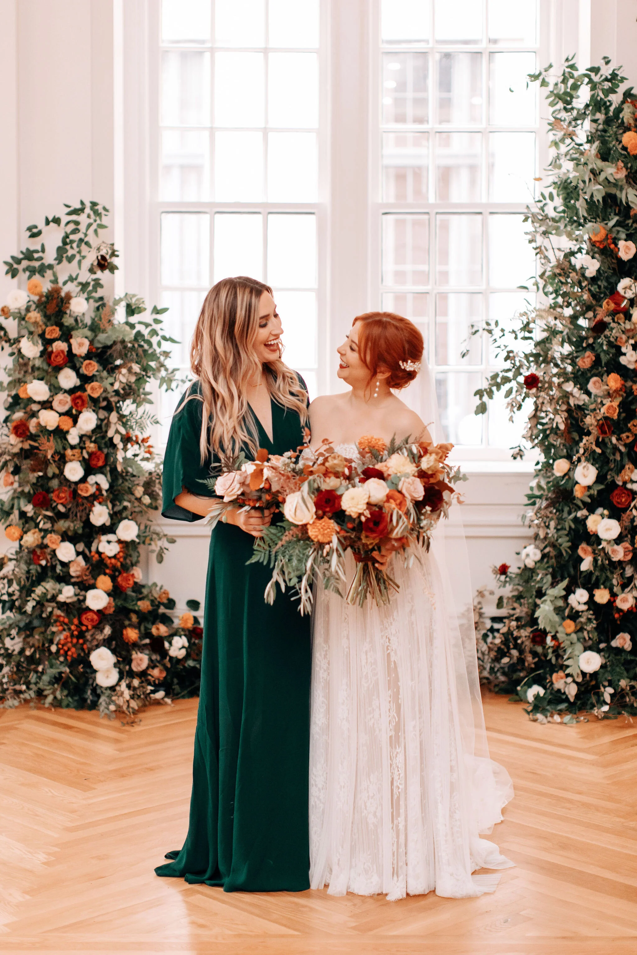Growing floral installation on either side of the window for the wedding ceremony backdrop, with untamed greenery, rusty orange and burnt sienna garden roses, and lots of texture. Nashville wedding florist at the Noelle hotel.