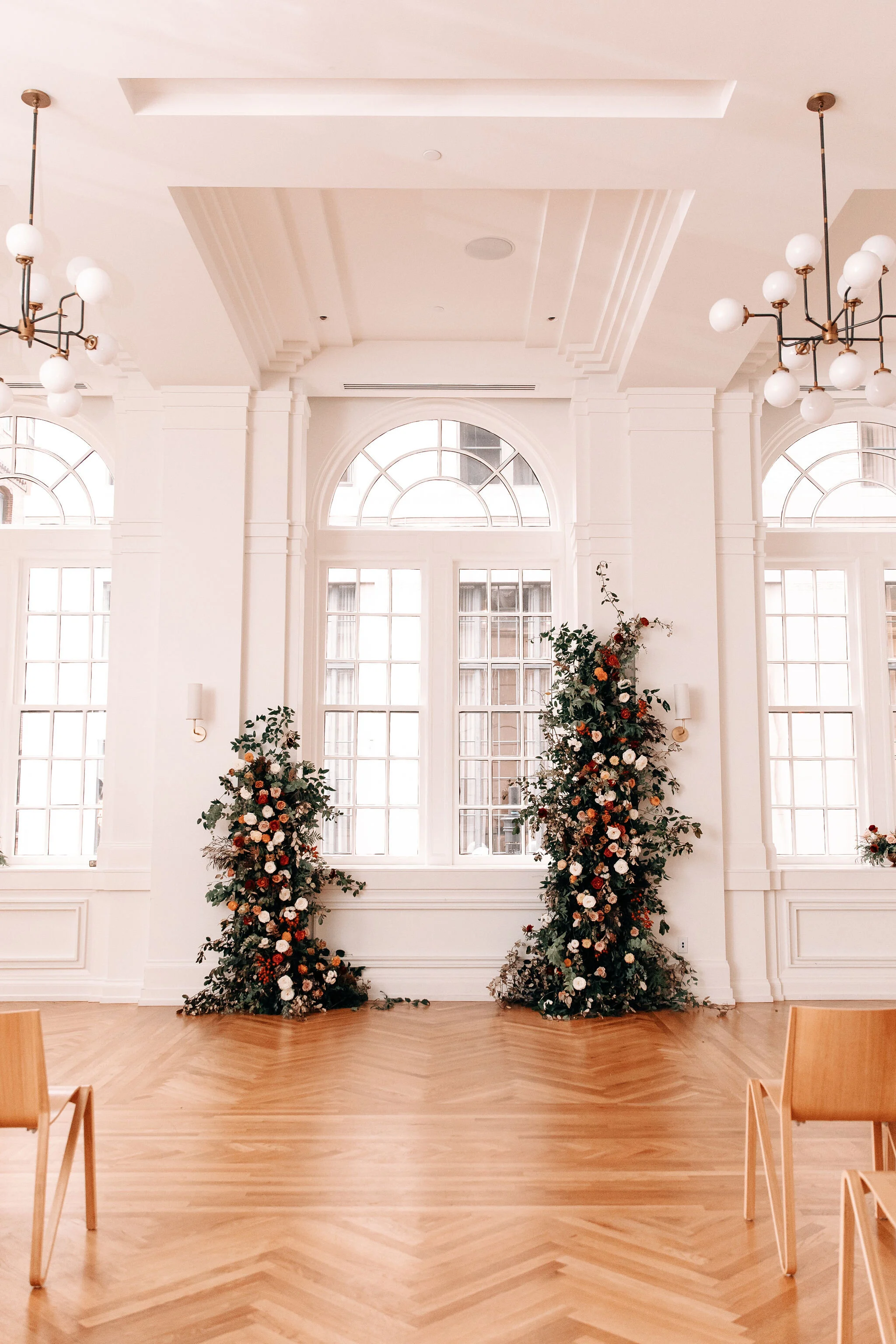 Growing floral installation on either side of the window for the wedding ceremony backdrop, with untamed greenery, rusty orange and burnt sienna garden roses, and lots of texture. Nashville wedding florist at the Noelle hotel.