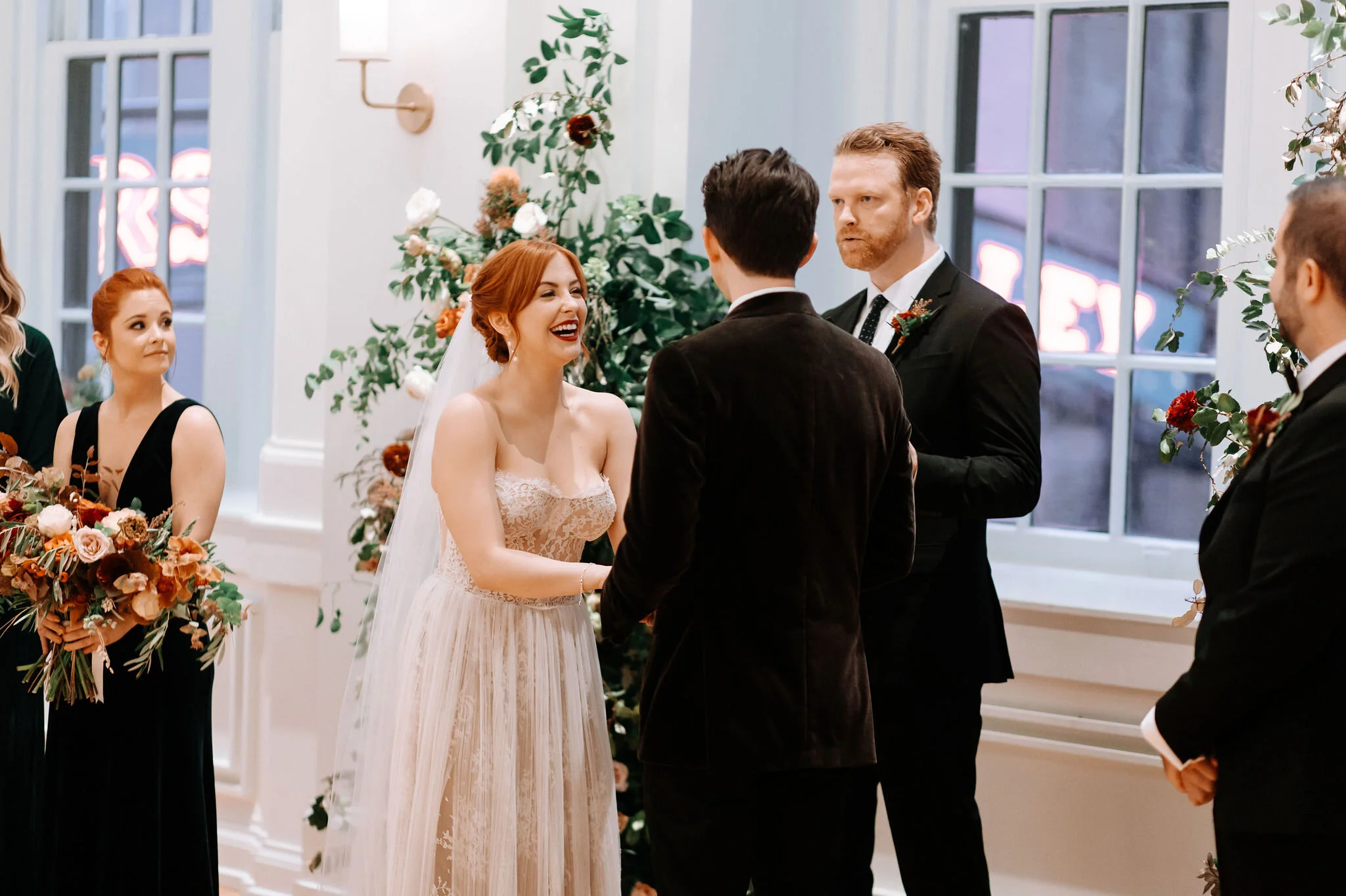 Growing floral installation on either side of the window for the wedding ceremony backdrop, with untamed greenery, rusty orange and burnt sienna garden roses, and lots of texture. Nashville wedding florist at the Noelle hotel.