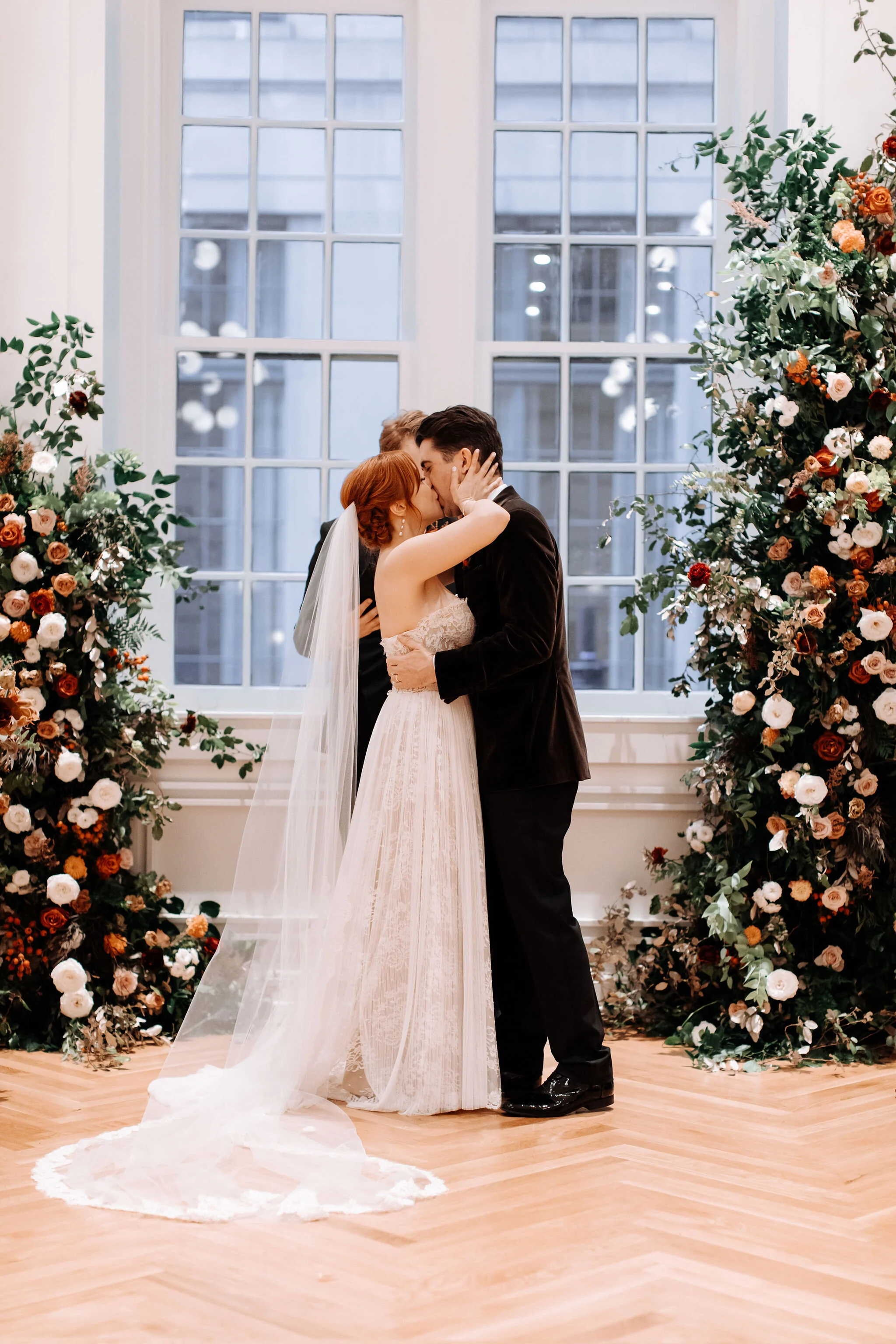 Growing floral installation on either side of the window for the wedding ceremony backdrop, with untamed greenery, rusty orange and burnt sienna garden roses, and lots of texture. Nashville wedding florist at the Noelle hotel.