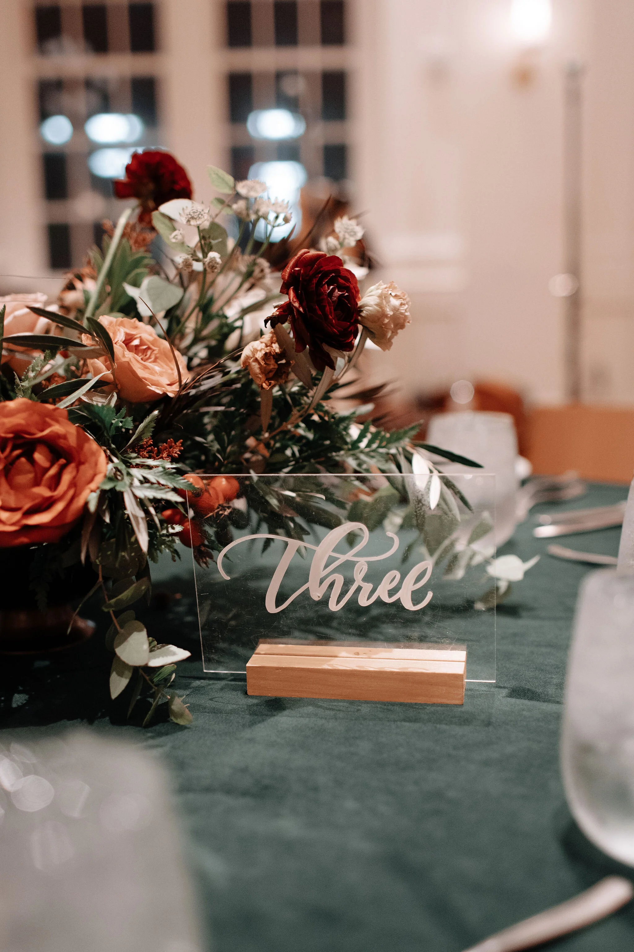 Green velvet linens, garden inspired low floral centerpieces with burnt orange garden roses, rusty red ranunculus, texture, olive branches, and greenery. Nashville wedding florist at the Noelle.