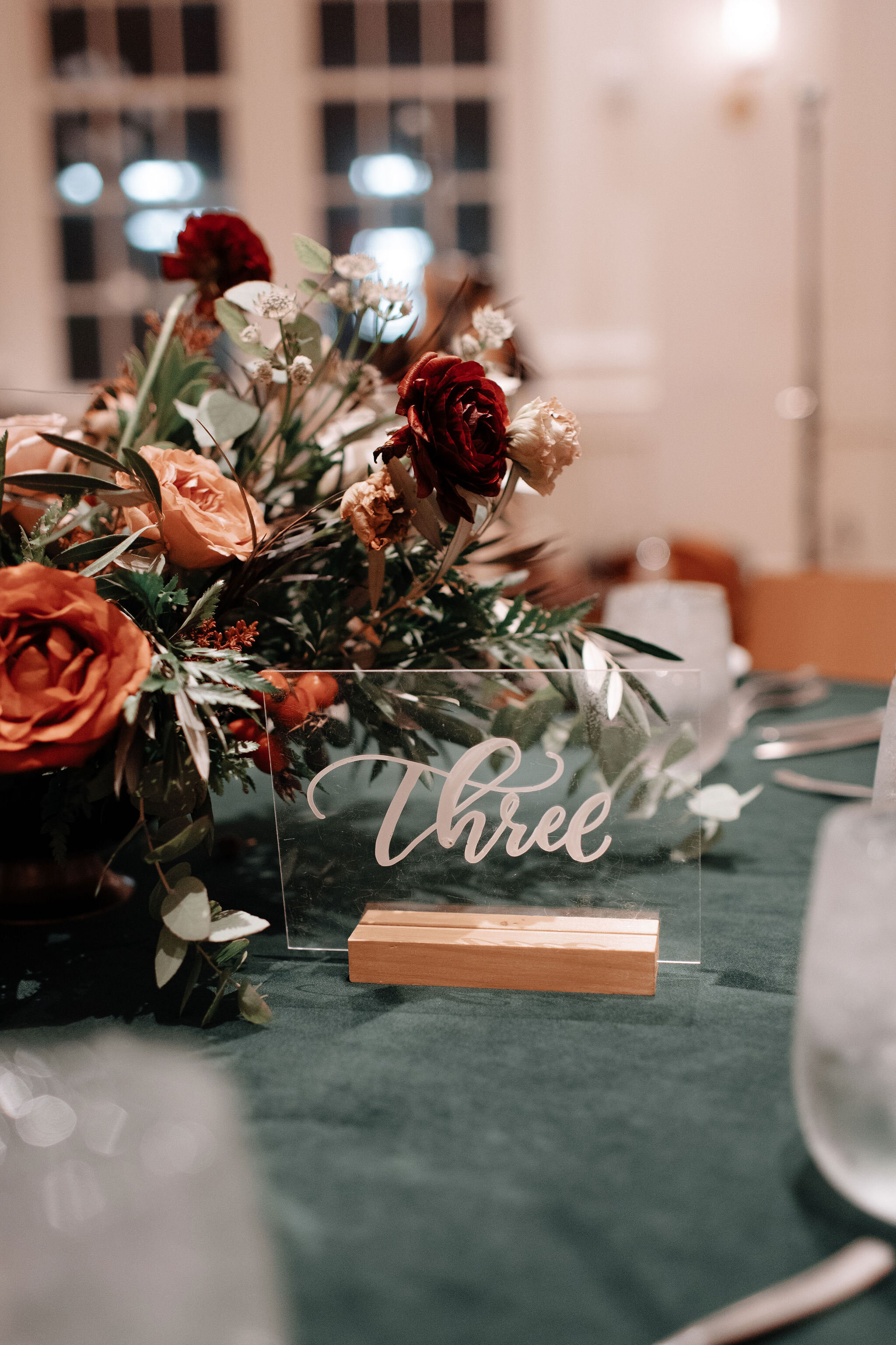 Green velvet linens, garden inspired low floral centerpieces with burnt orange garden roses, rusty red ranunculus, texture, olive branches, and greenery. Nashville wedding florist at the Noelle.