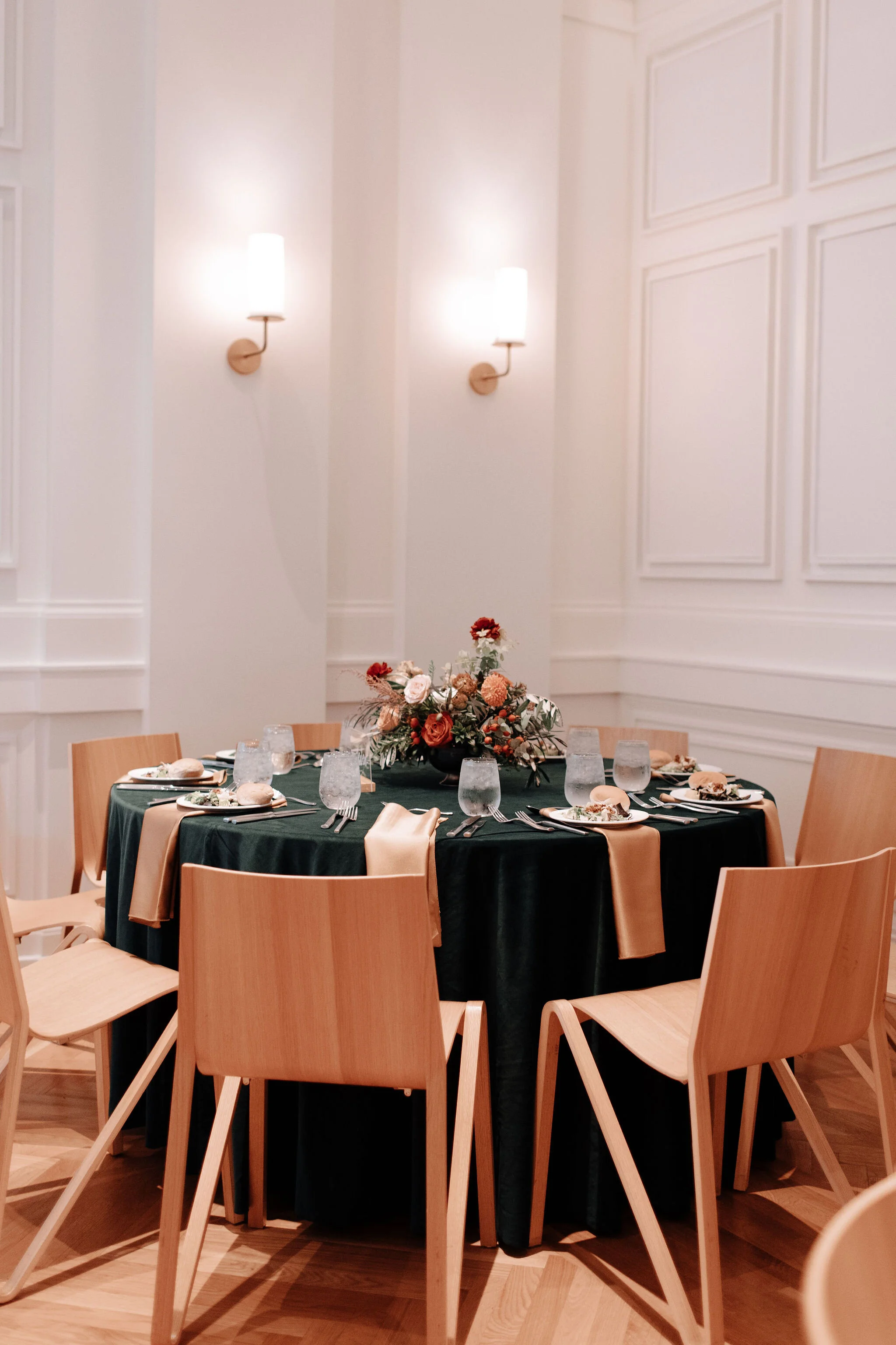 Green velvet linens, garden inspired low floral centerpieces with burnt orange garden roses, rusty red ranunculus, texture, olive branches, and greenery. Nashville wedding florist at the Noelle.