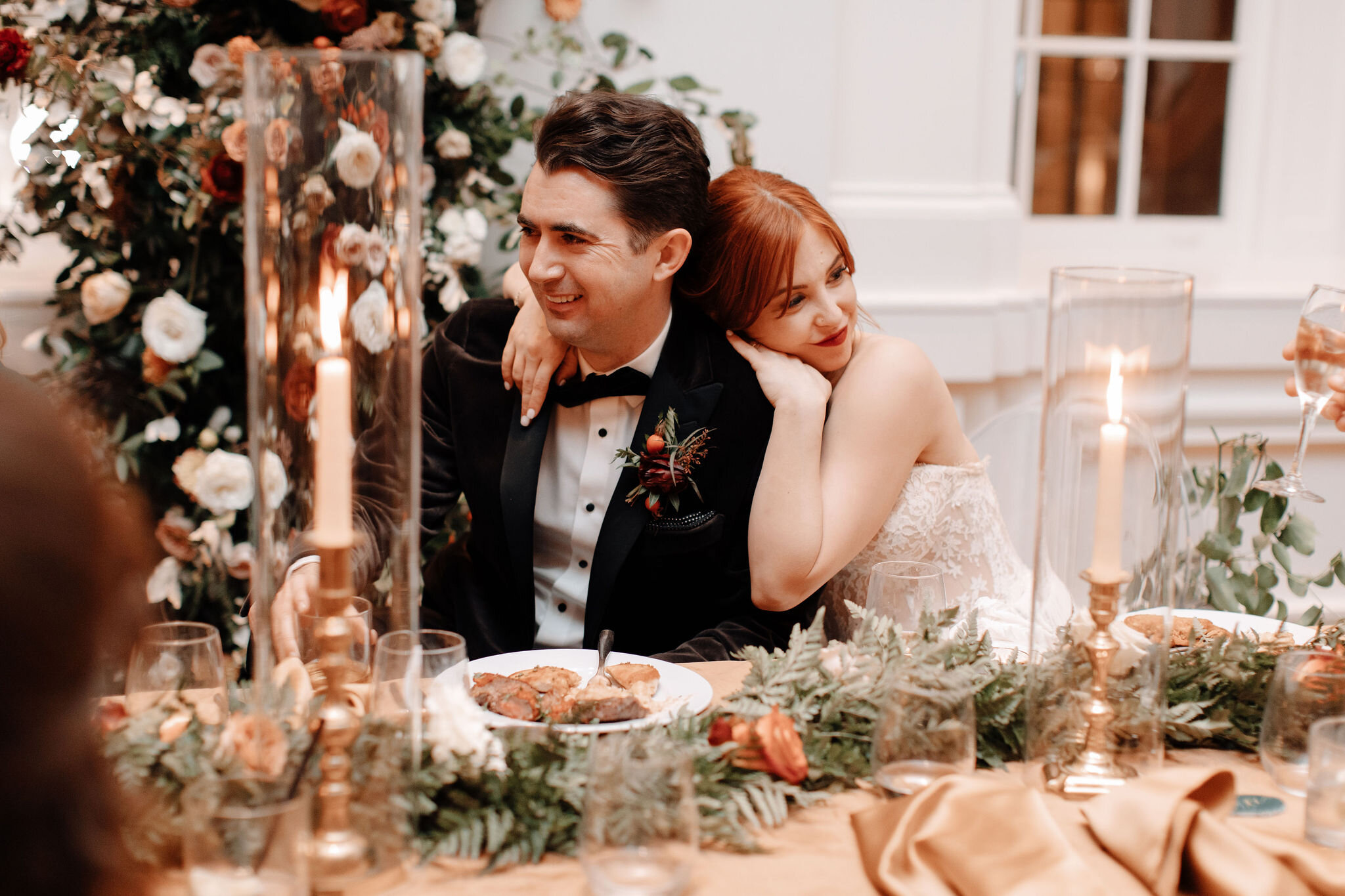 Head table with rust velvet linen, lush garland of ferns and burnt orange garden roses, and brass candlesticks. Nashville wedding florist at the Noelle hotel.