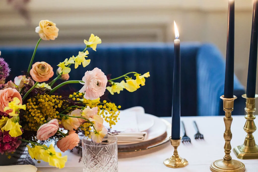 Low, colorful, modern floral centerpiece with ranunculus, sweet peas, acacia, and allium. Tennessee wedding florist.
