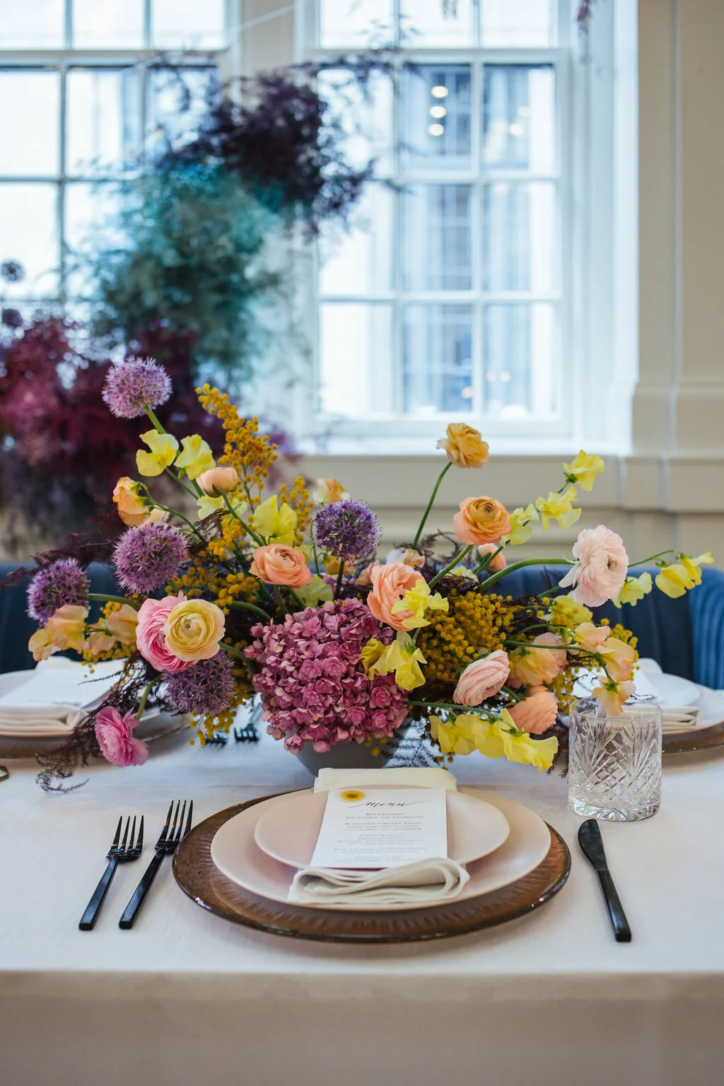 Low, colorful, modern floral centerpiece with ranunculus, sweet peas, acacia, and allium. Tennessee wedding florist.