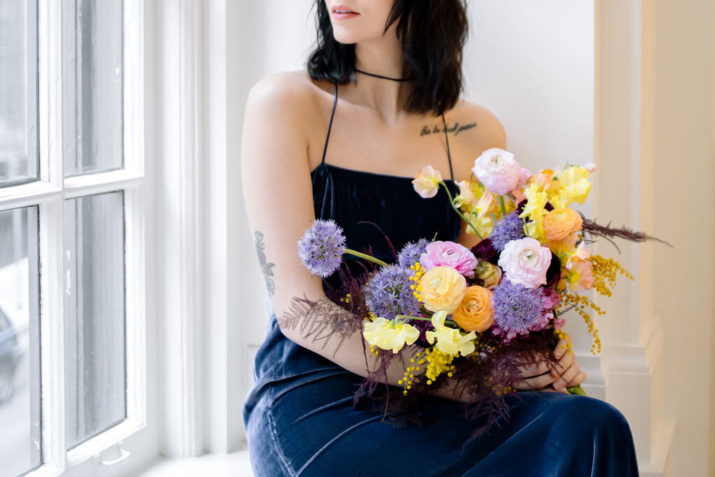 Modern, colorful bridal bouquet with yellow sweet peas, purple allium, pink and peach ranunculus, golden acacia, and painted eggplant plums fern. Nashville wedding florist.