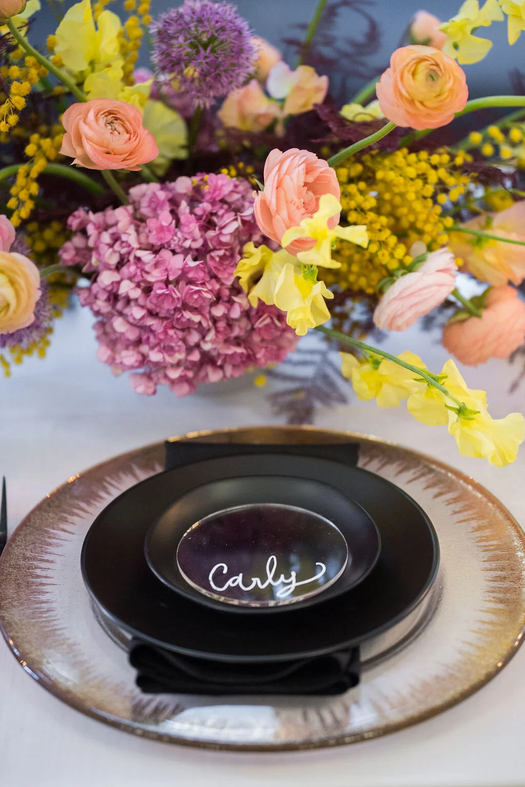 Low, colorful, modern floral centerpiece with ranunculus, sweet peas, acacia, and allium. Tennessee wedding florist.