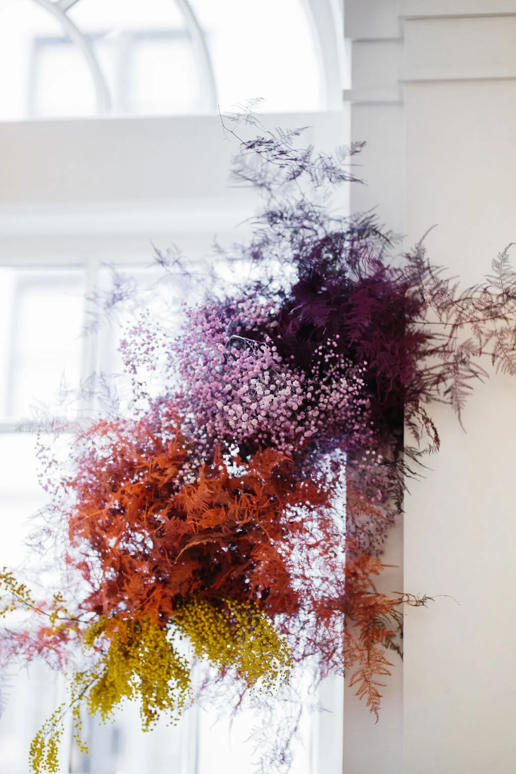 Rainbow colored floral installation with painted and dyed baby’s breath and plums ferns. Modern, minimal, colorful wedding flowers at the Noelle Hotel in downtown Nashville.