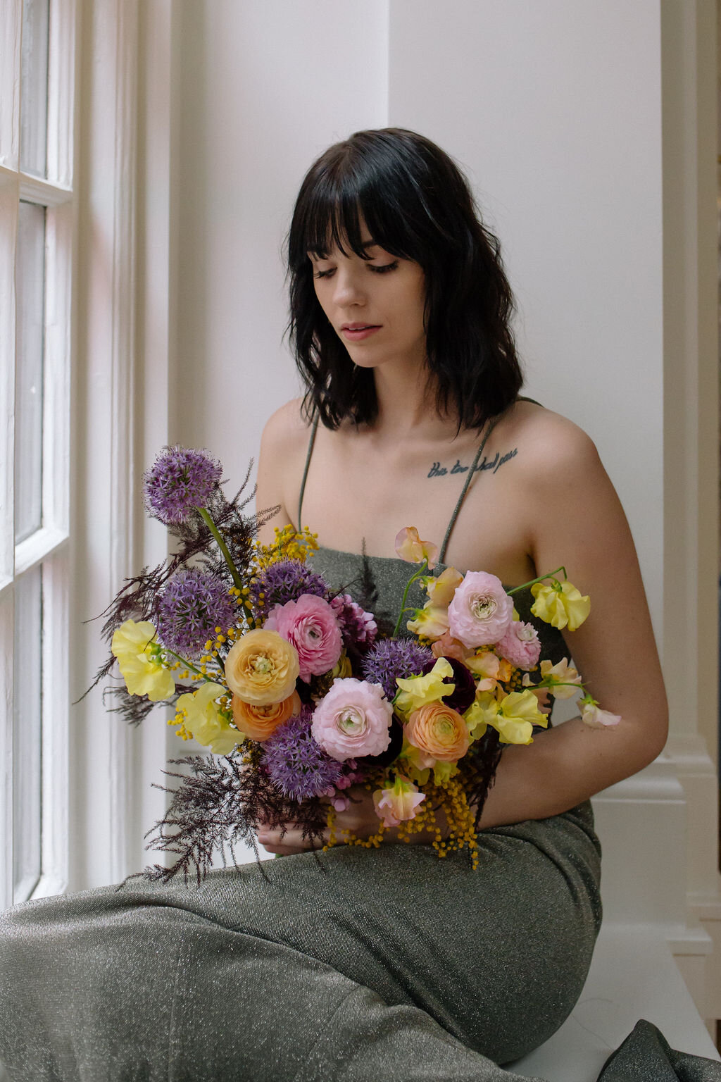 Modern, colorful bridal bouquet with yellow sweet peas, purple allium, pink and peach ranunculus, golden acacia, and painted eggplant plums fern. Nashville wedding florist. Printer’s Alley portraits.