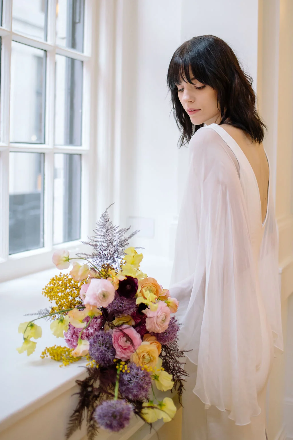 Modern, colorful bridal bouquet with yellow sweet peas, purple allium, pink and peach ranunculus, golden acacia, and painted eggplant plums fern. Nashville wedding florist. Printer’s Alley portraits.