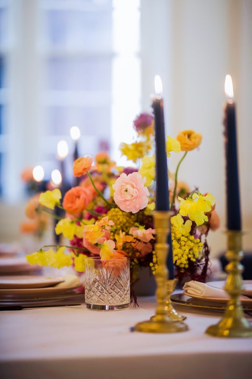 Low, colorful, modern floral centerpiece with ranunculus, sweet peas, acacia, and allium. Tennessee wedding florist.