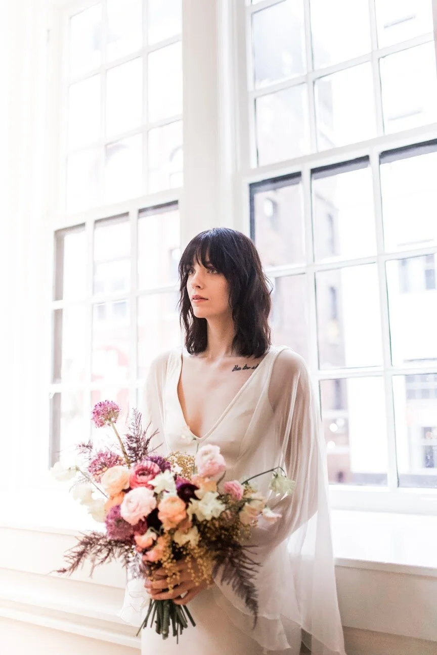 Modern, colorful bridal bouquet with yellow sweet peas, purple allium, pink and peach ranunculus, golden acacia, and painted eggplant plums fern. Nashville wedding florist. Printer’s Alley portraits.