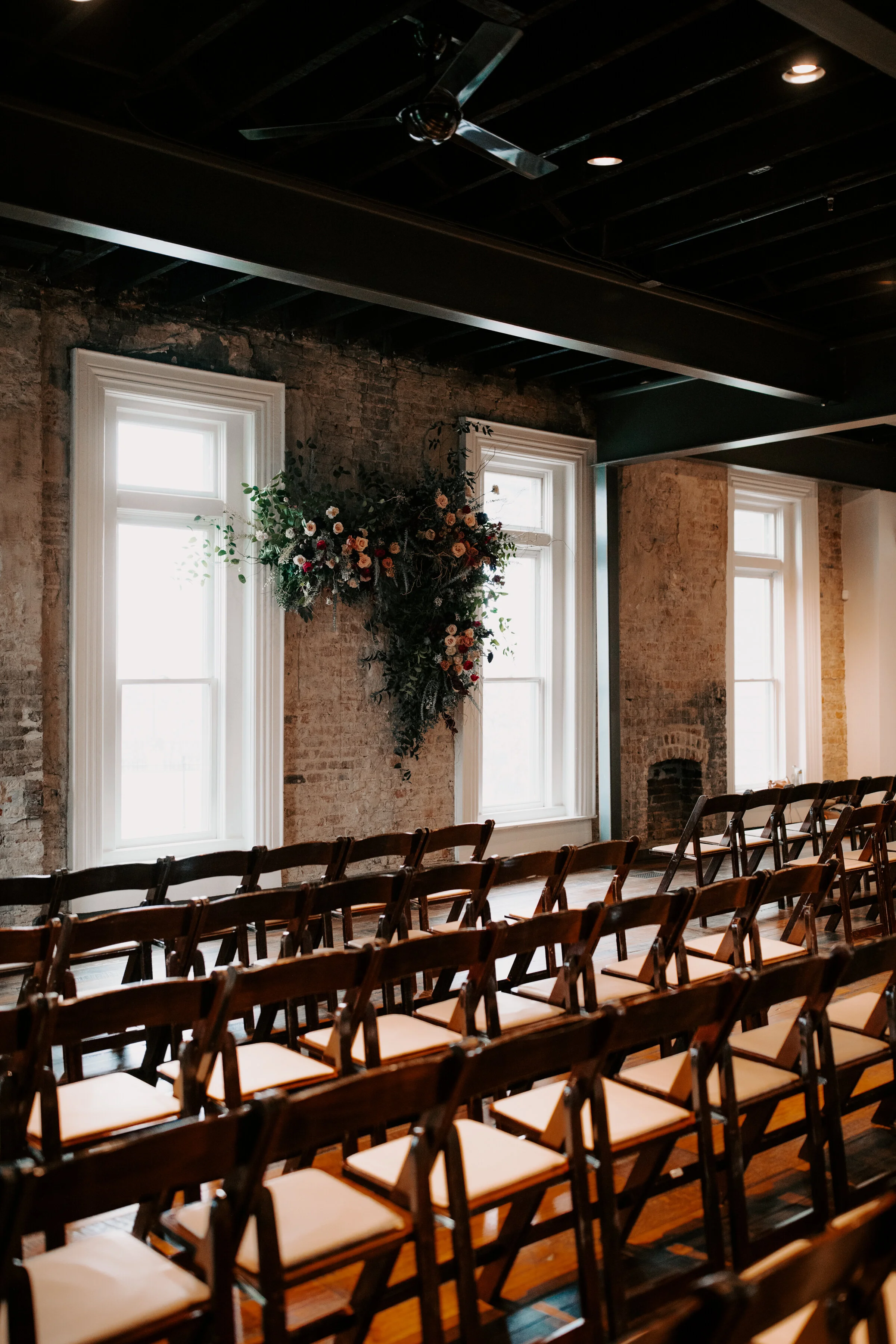 Organic, hanging floral installation for the wedding ceremony backdrop with lush greenery, curly willow branches, and earth toned and burgundy flowers. Nashville wedding florist at the Cordelle.