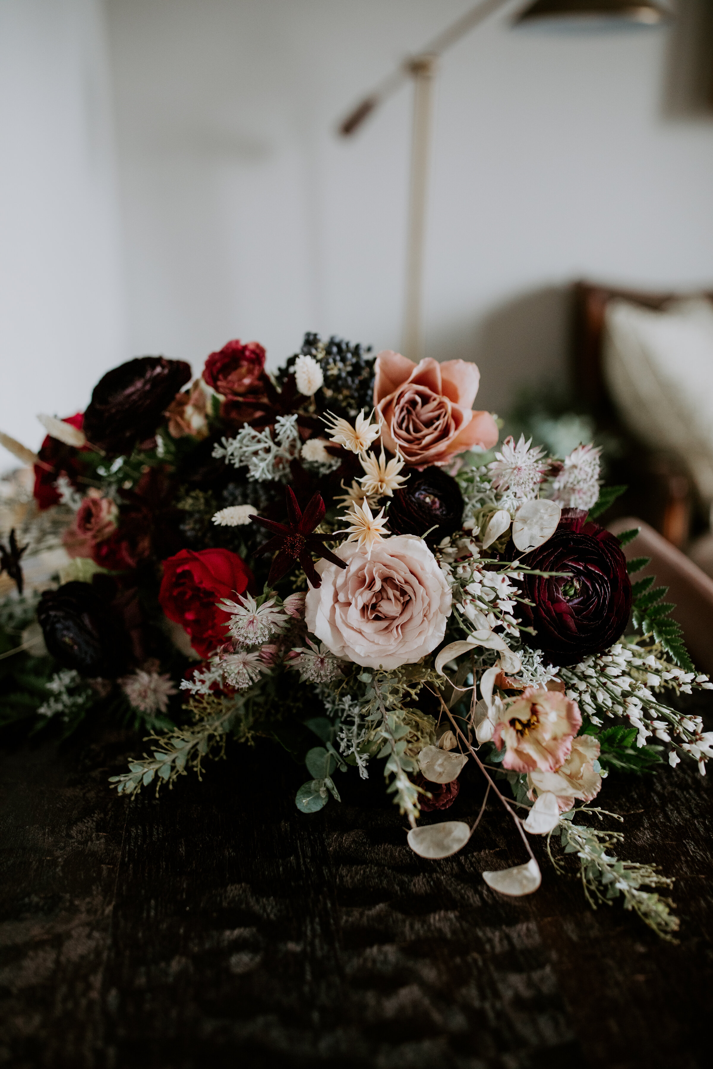 Loose, whimsical winter bridal bouquet with eggplant, blush, mauve, and burgundy garden roses and ranunculus, dried flowers, and natural, untamed greenery. Nashville wedding floral design at the Cordelle.